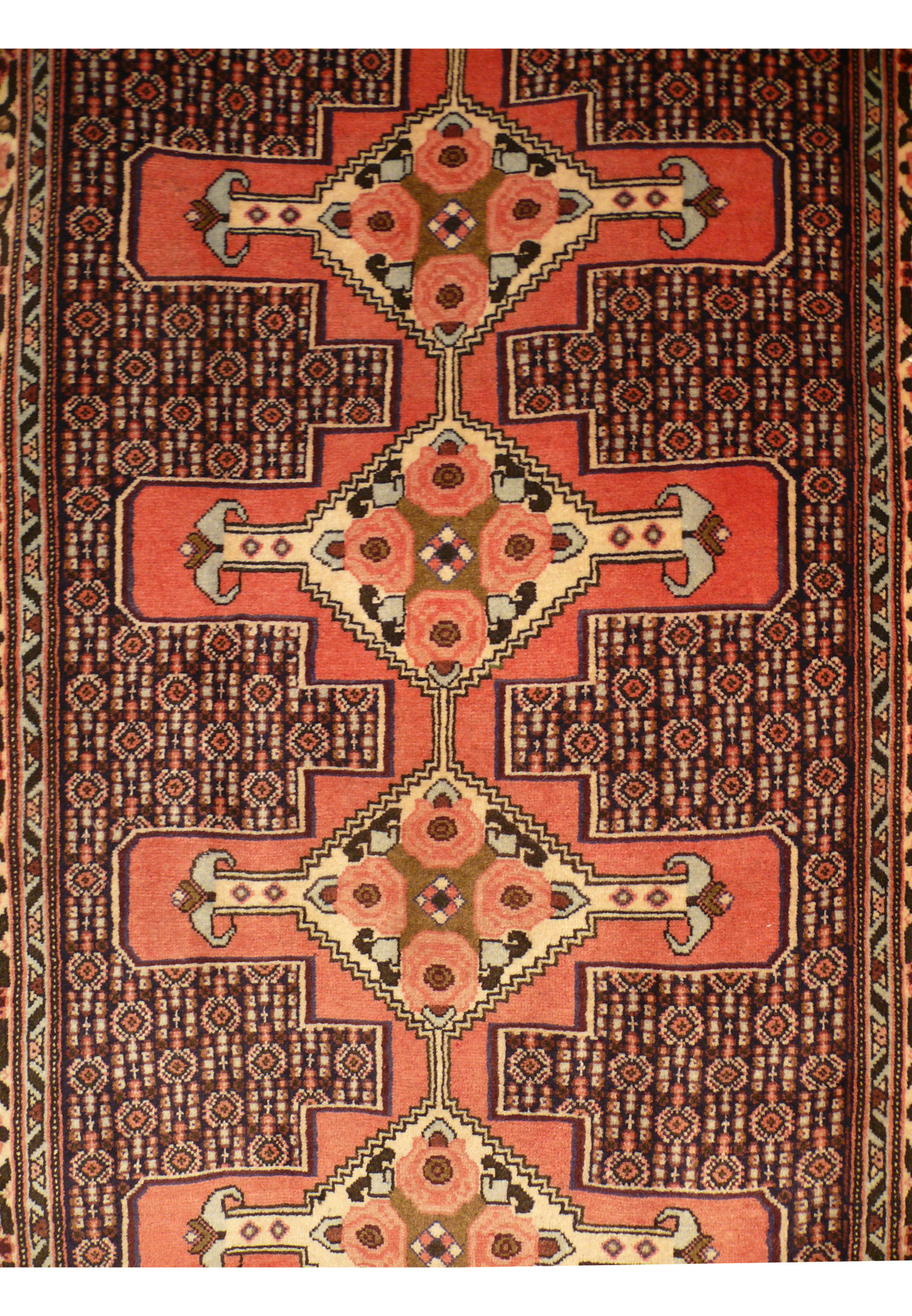 Detailed field section of handmade Persian runner with repeating boteh style forms and dense fine knot weaving