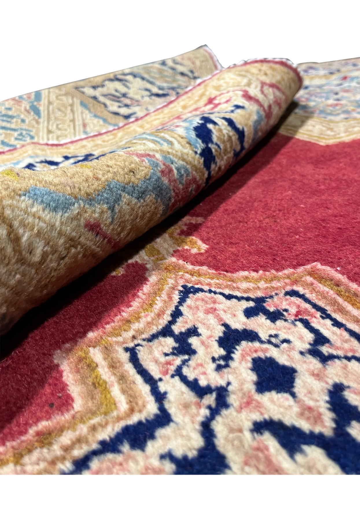 Rolled Persian Kerman rug demonstrating flexible wool foundation, thickness and sturdy hand knotted construction