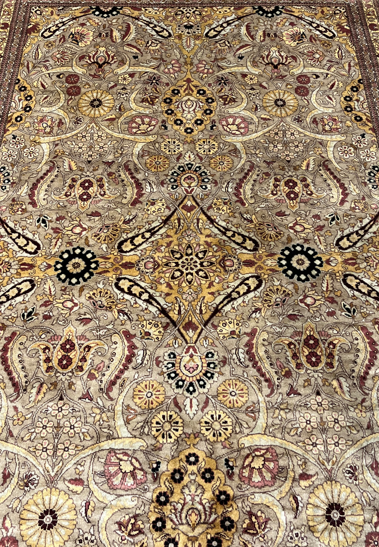 Closeup of central medallion area with golden motifs, rust florals, and fine hand knotted detail.