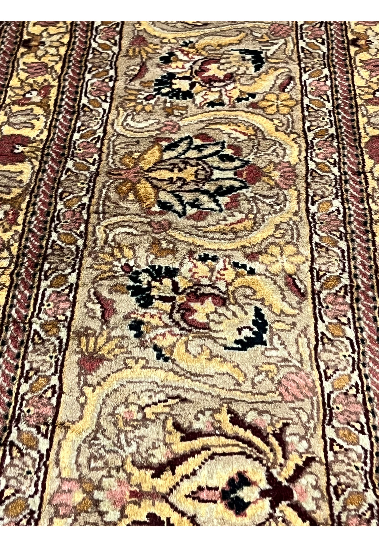 Closeup of Agra rug border with floral cartouches, beige tan ground, burgundy and gold accents, showing detailed hand knotted wool texture