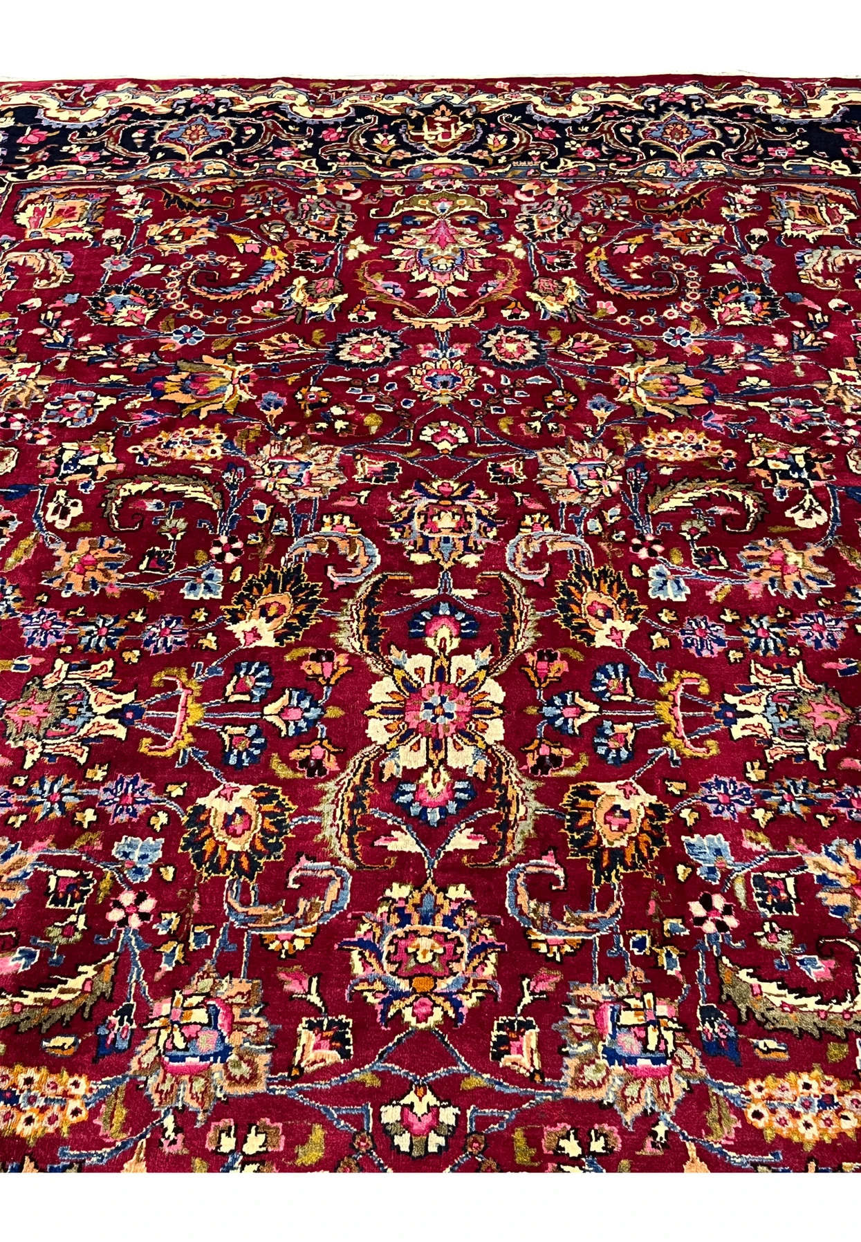 Close view of Mashad rug field showing dense floral arabesques, vibrant red background, and fine wool knotting