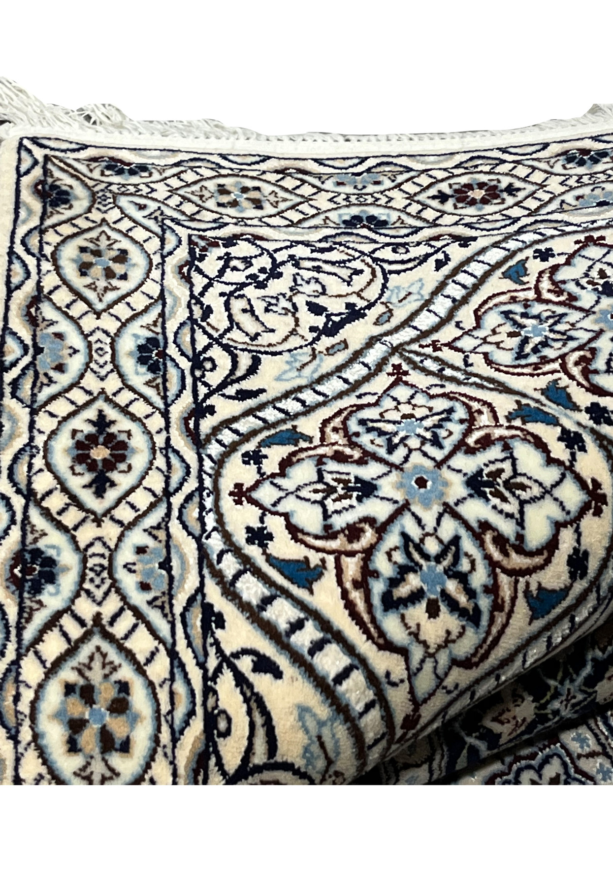 Folded edge of Persian Nain Habibian 6 LA rug with ivory border navy and light blue floral motifs silk accents.