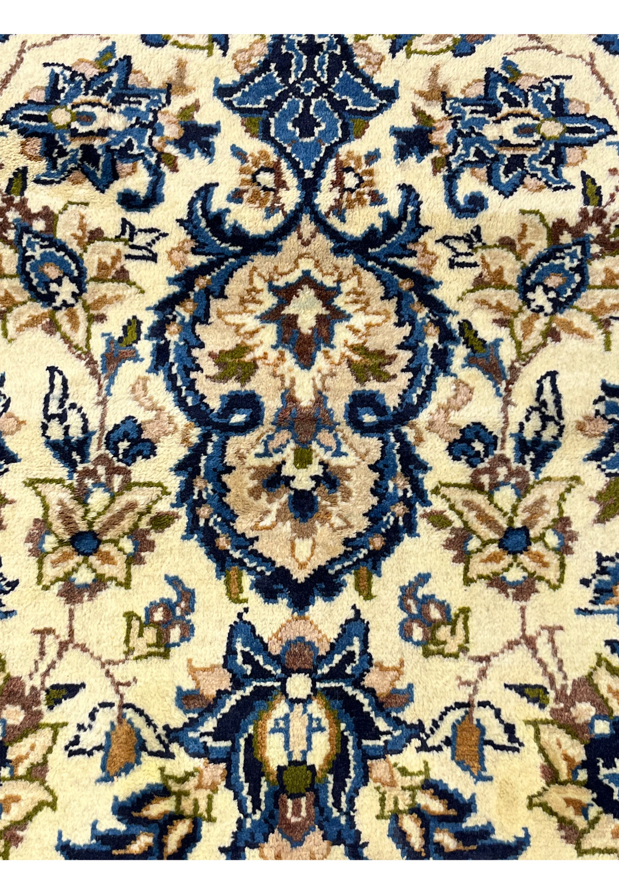 Persian Kashan rug pattern closeup featuring ivory background blue floral motifs symmetrical vine scrolls and dense handmade wool knots