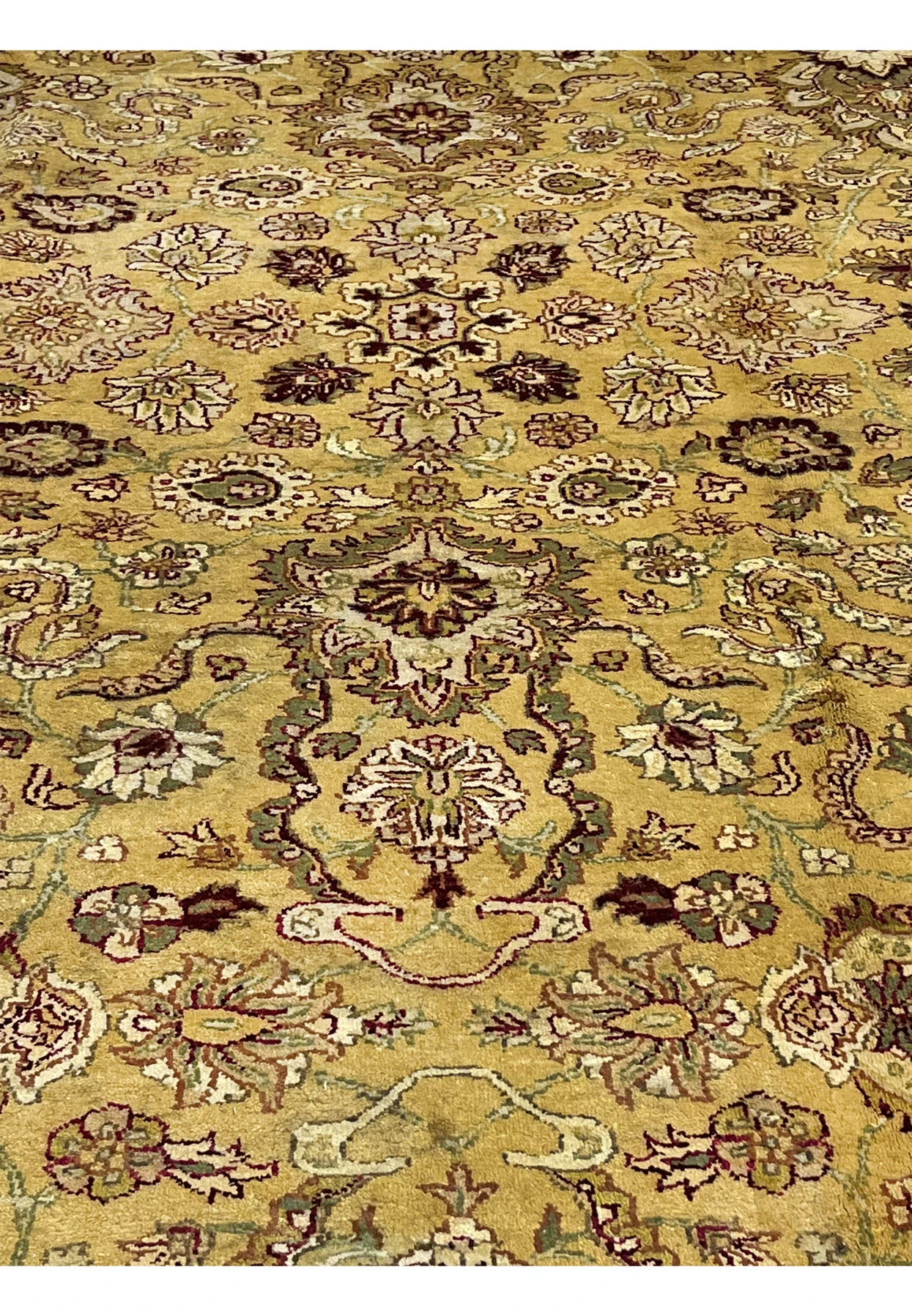 Antique style Indian Agra rug closeup highlighting central floral medallion motifs with ivory accents and deep burgundy outlines.