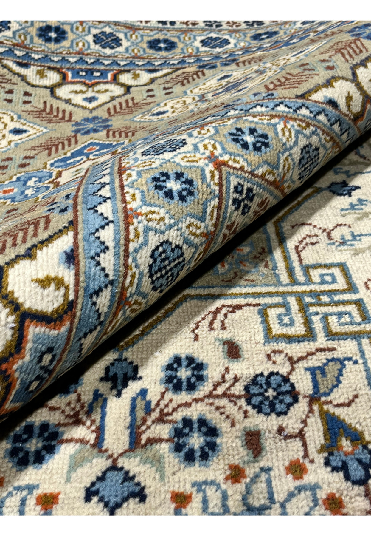 Close-up of the back of a Persian Tabriz rug with a leather binding strip visible along the edge, showing the tightly woven reverse with clearly defined pattern outlines confirming high knot density and hand-knotted craftsmanship.