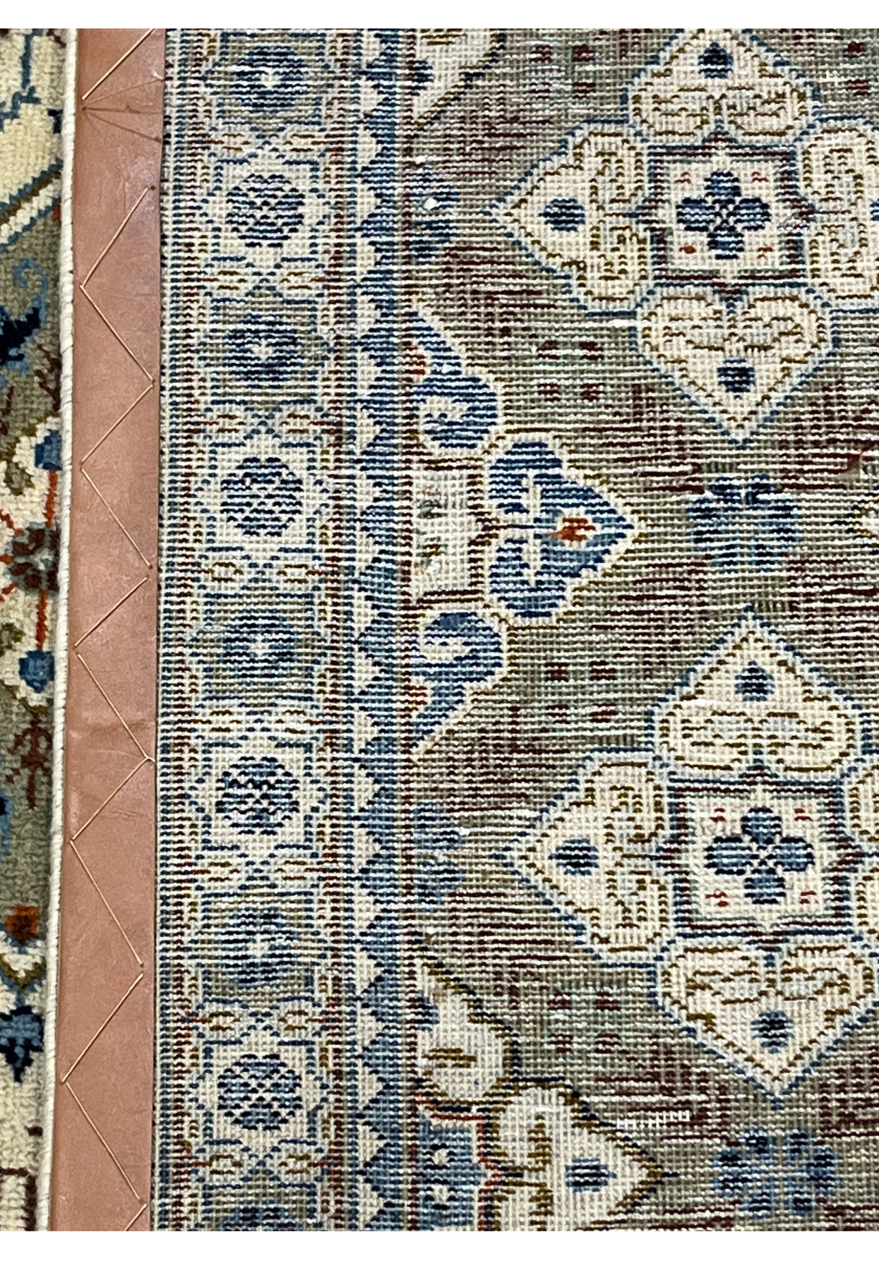 Underside corner of a Tabriz rug folded back to reveal the tightly woven cotton foundation, the neat selvedge edge, and the consistent knot structure on the reverse, confirming hand-knotted construction.