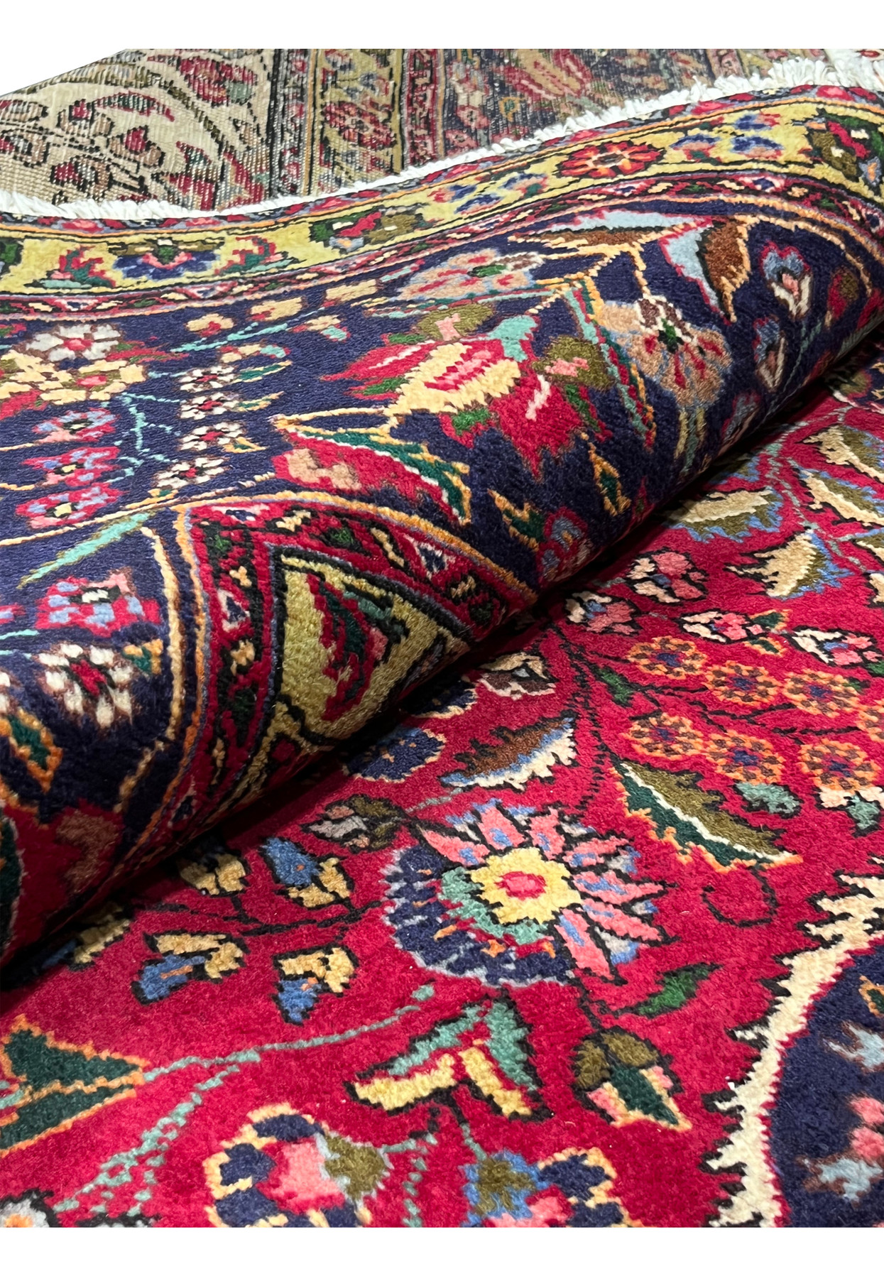 Rolled view of 10x13 Persian Tabriz rug showing deep red pile and floral border