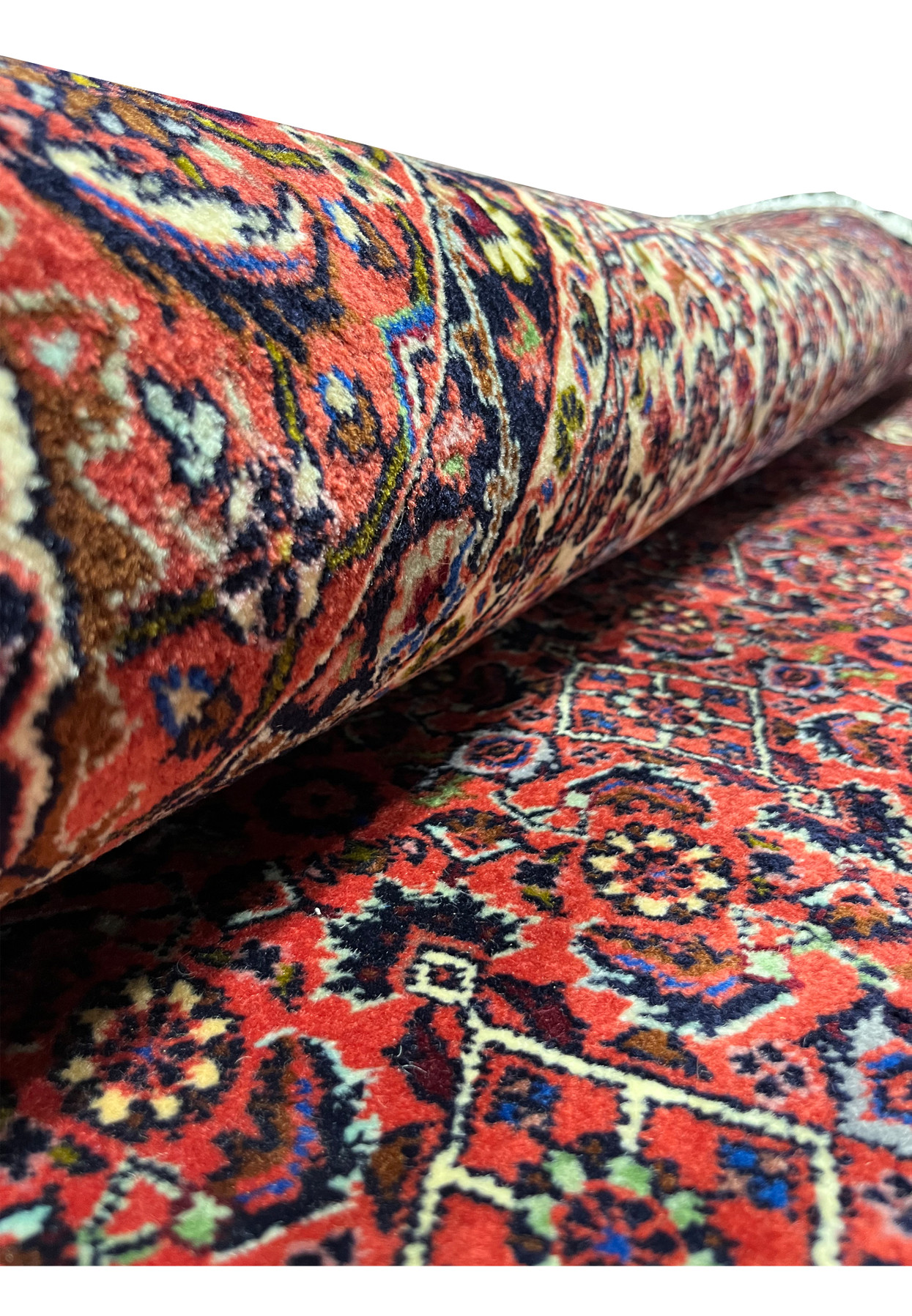 Rolled Persian Bijar rug showing dense hand-knotted wool pile and red border detail