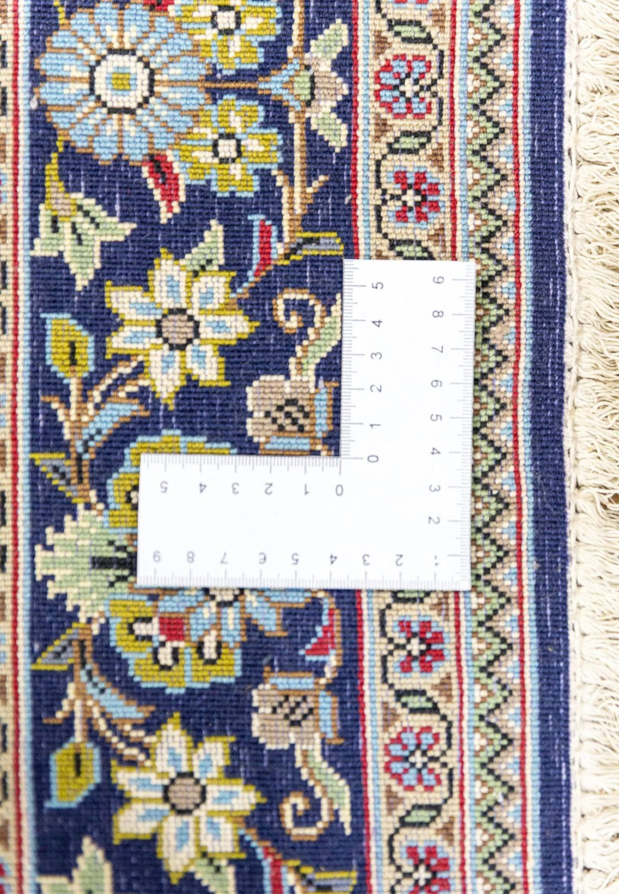 Backside of Persian Qum rug measured at 400 knots per square inch with ruler showing dense fine weave