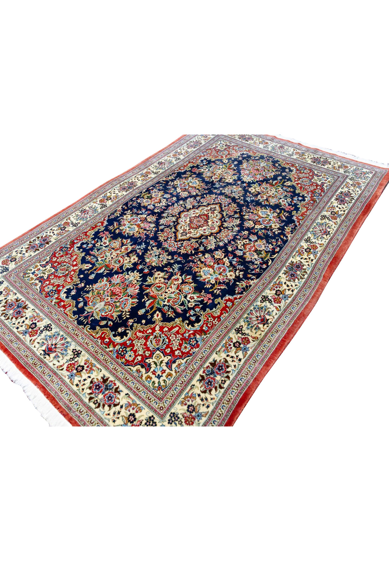 Persian Qum kork wool rug angled view showing navy field, brick red spandrels, and ivory floral border