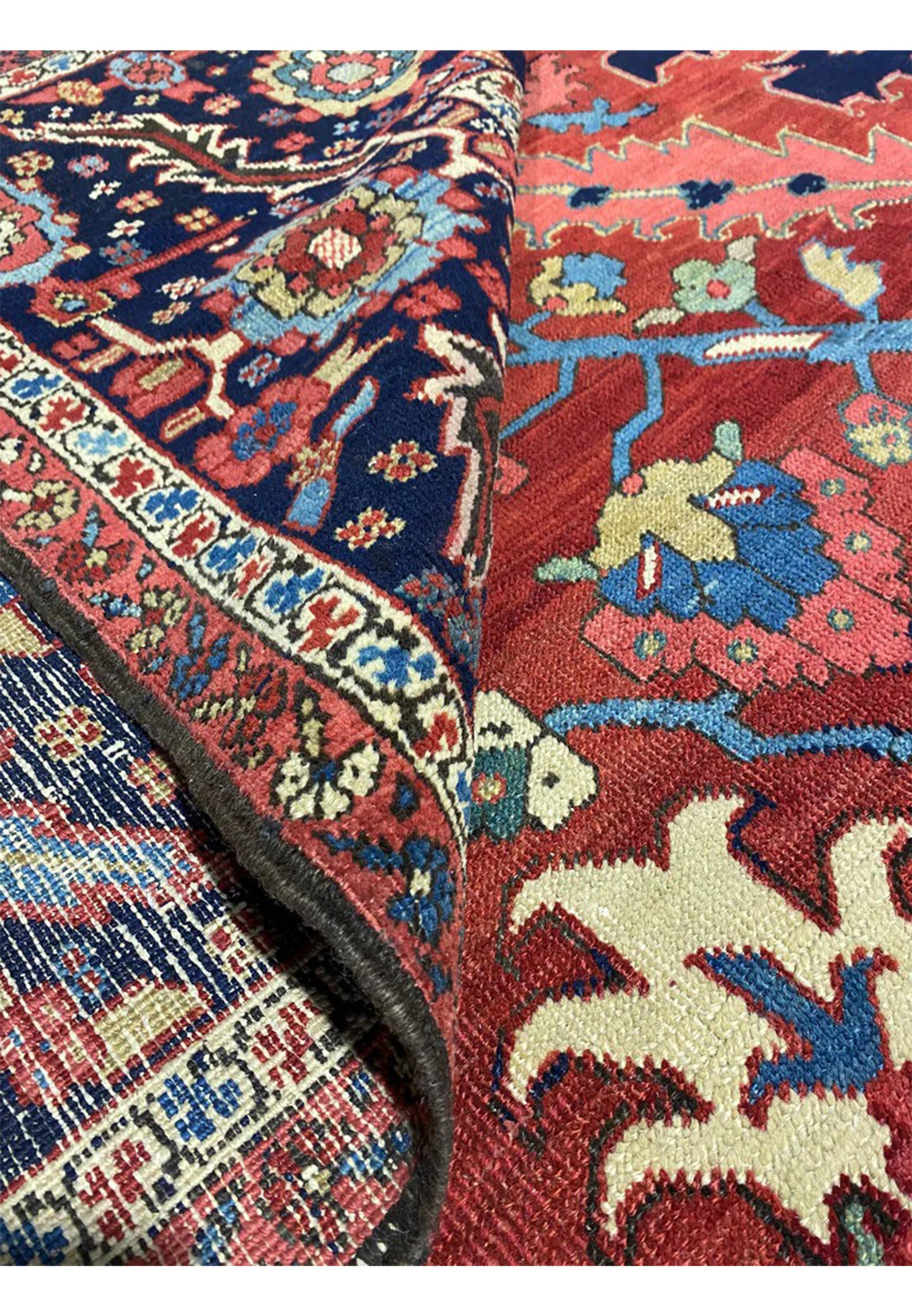 Rolled antique Persian Serapi Heriz rug showing soft wool pile and 1930s madder red ground tone