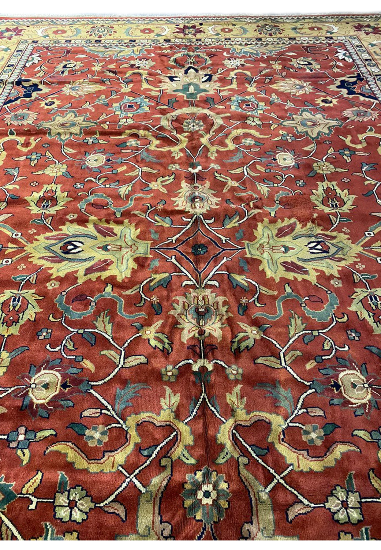 Midfield detail of soft tomato red Agra rug with serrated palmettes, navy cloud-bands, and curling vines
