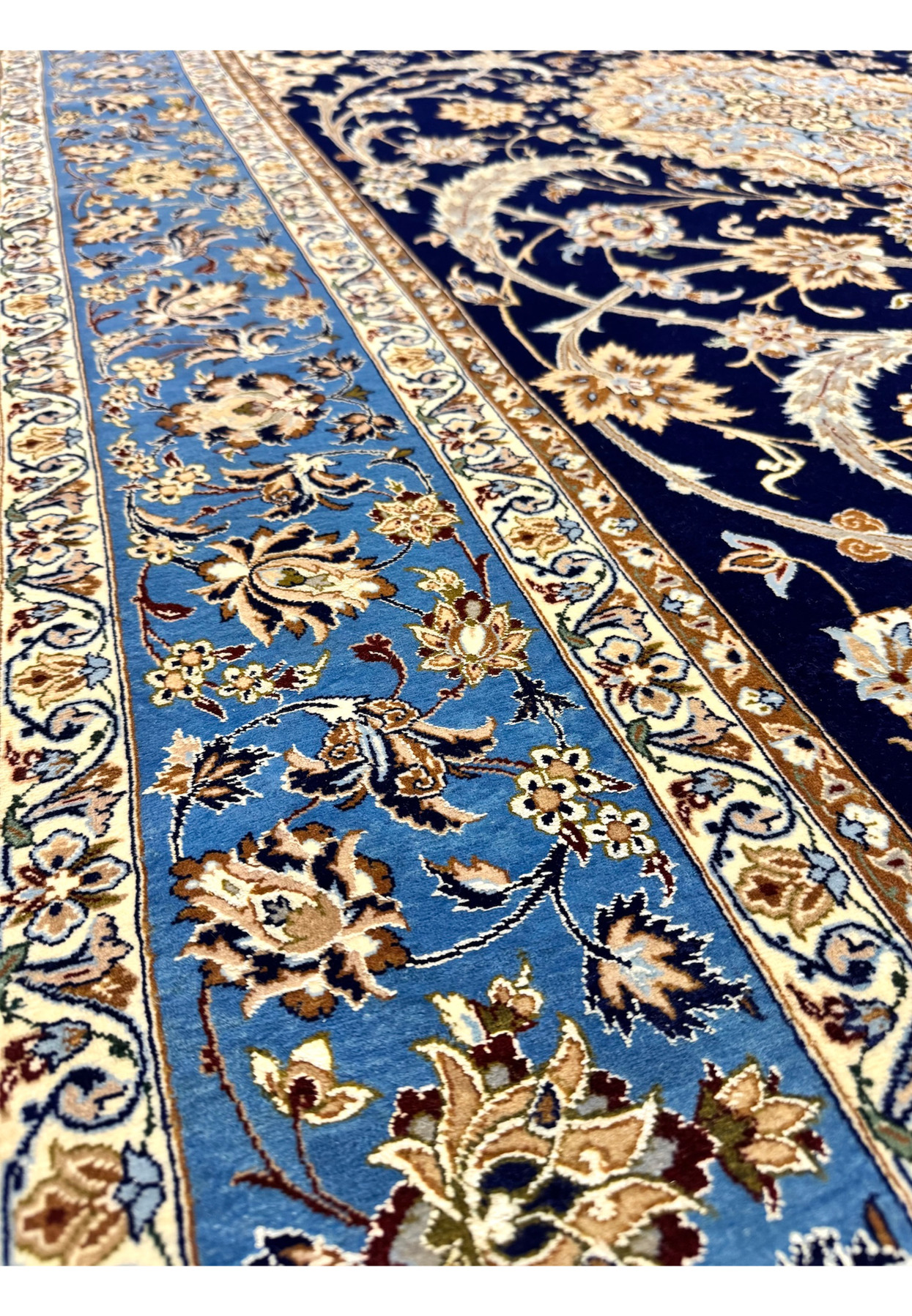 Border closeup of authentic Persian Isfahan rug with palmette and vine repeat on luminous light blue ground