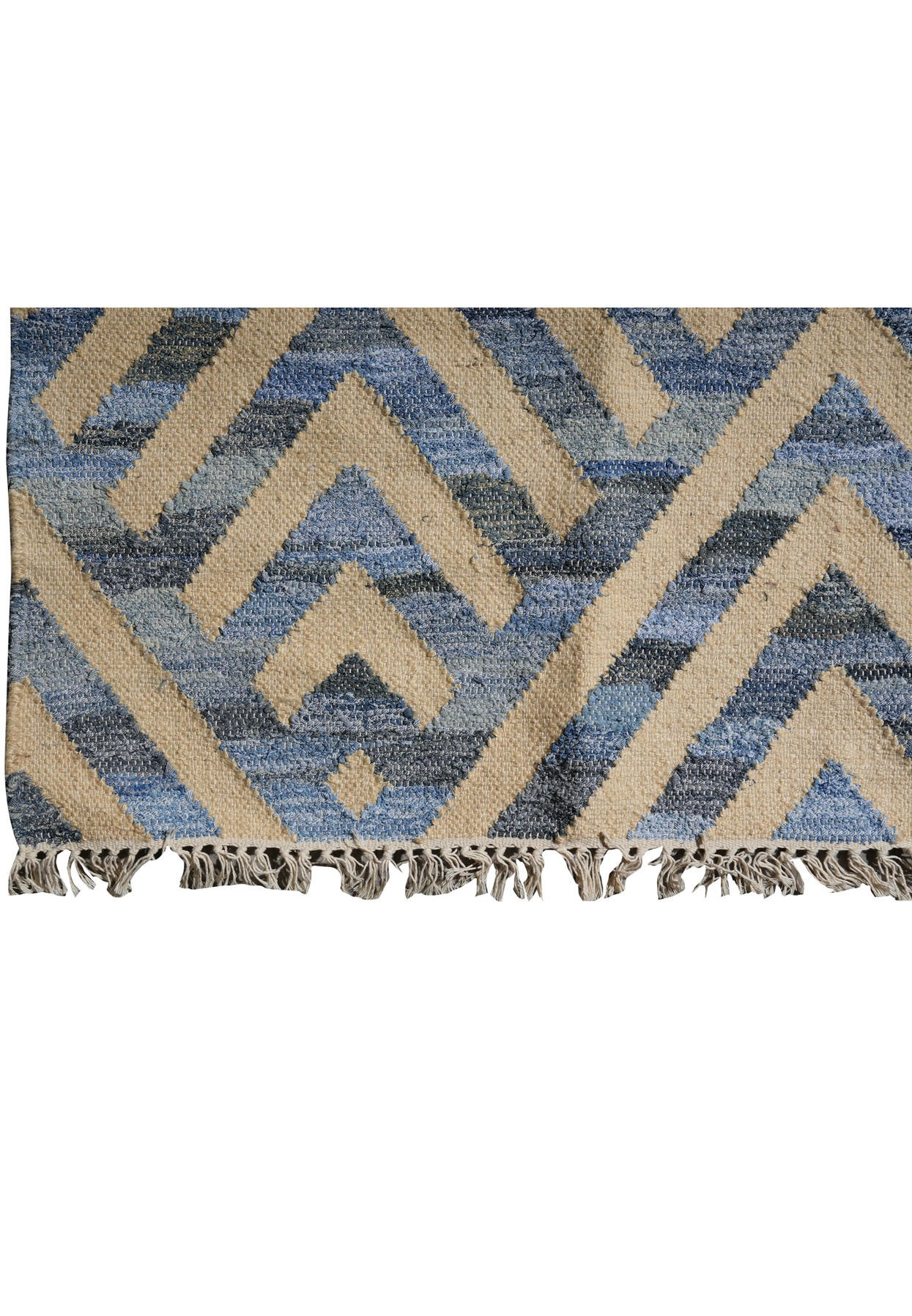 Corner detail with cotton fringe and the zigzag chevron border meeting the cream field along the rug edge