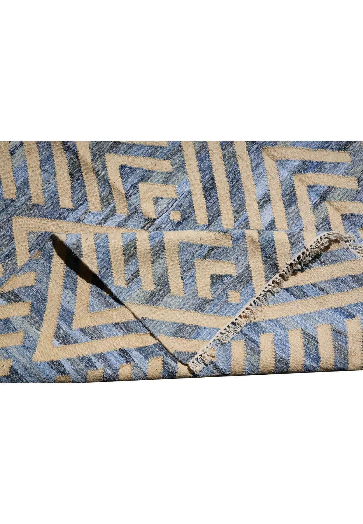 Folded corner of the blue and cream flatweave revealing the reverse side and the tight cotton weave structure