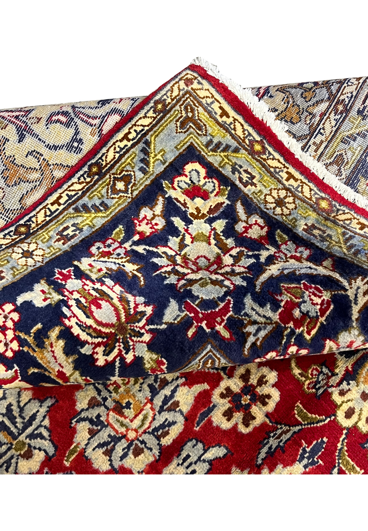 Folded corner showing the deep red field meeting the navy border with the dense wool pile clearly visible from both sides