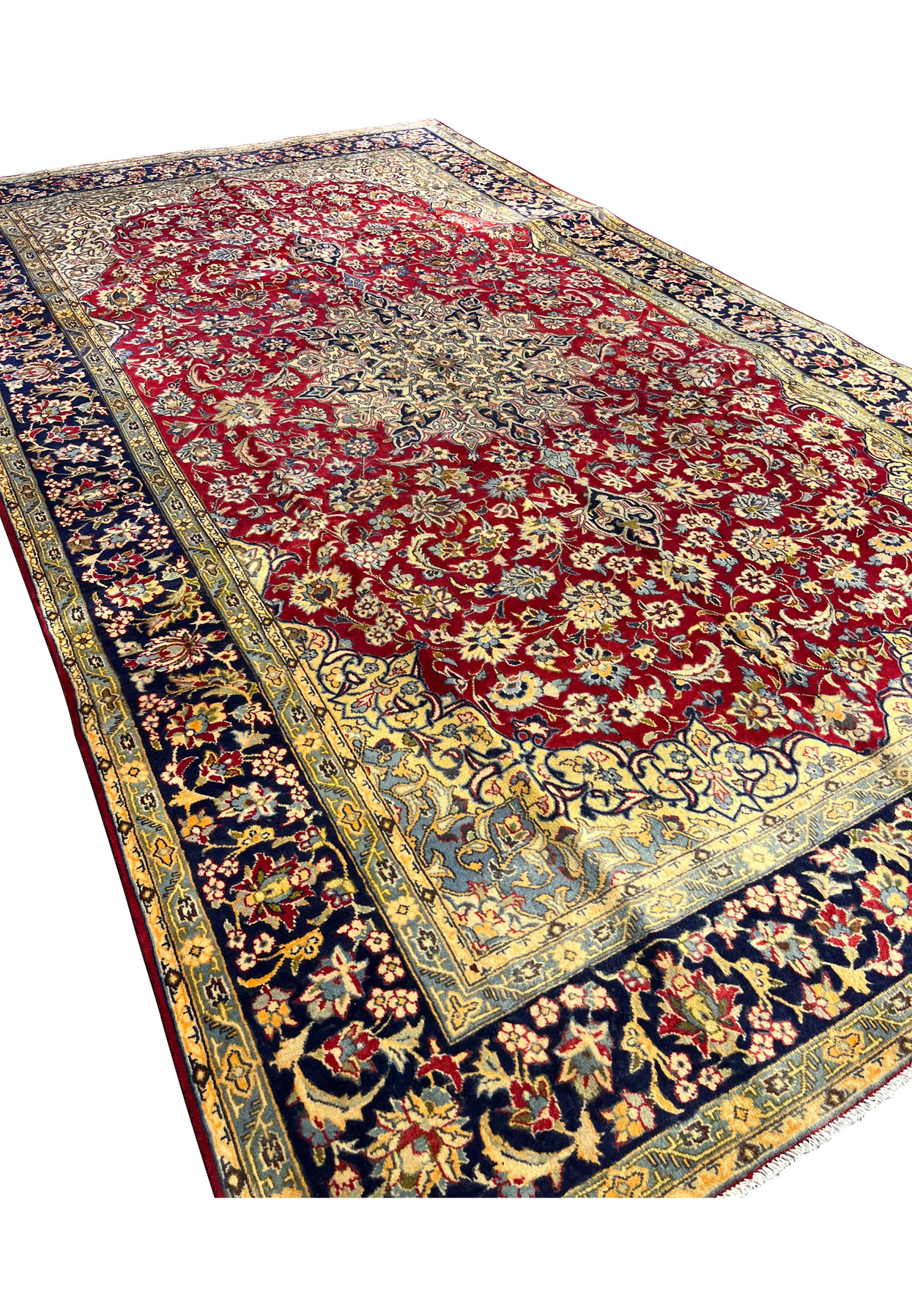 Angled three-quarter view of the deep red Isfahan revealing scale and the precise curvilinear drawing across the field