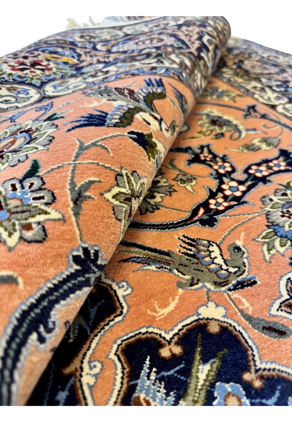Rolled view of the Davari Isfahan showing the fold drape, the silk highlights of the field, and the depth of the navy main border