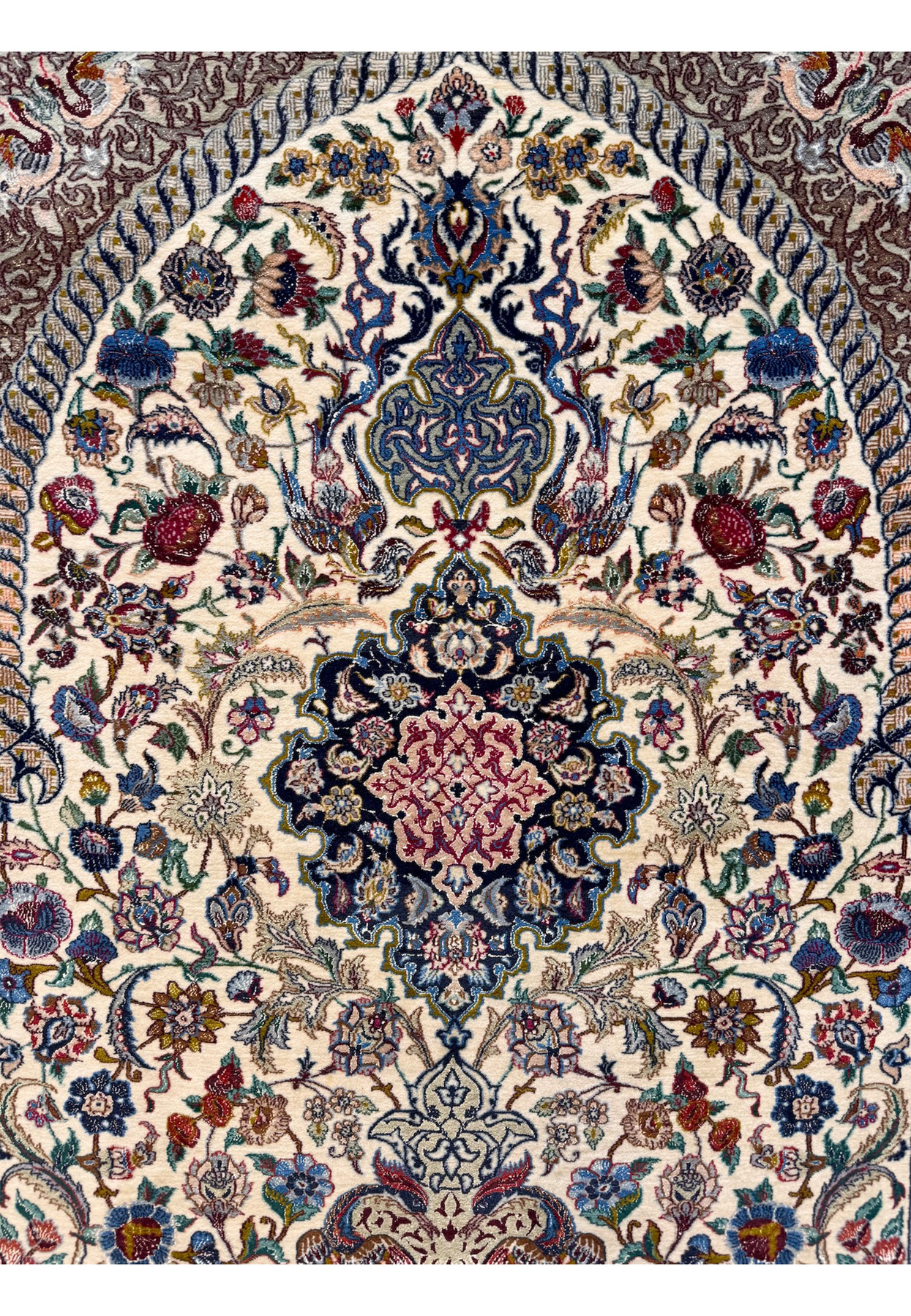 Upper field detail showing the tall ivory mihrab arch rising from the central medallion filled with vines, palmettes, and ground birds