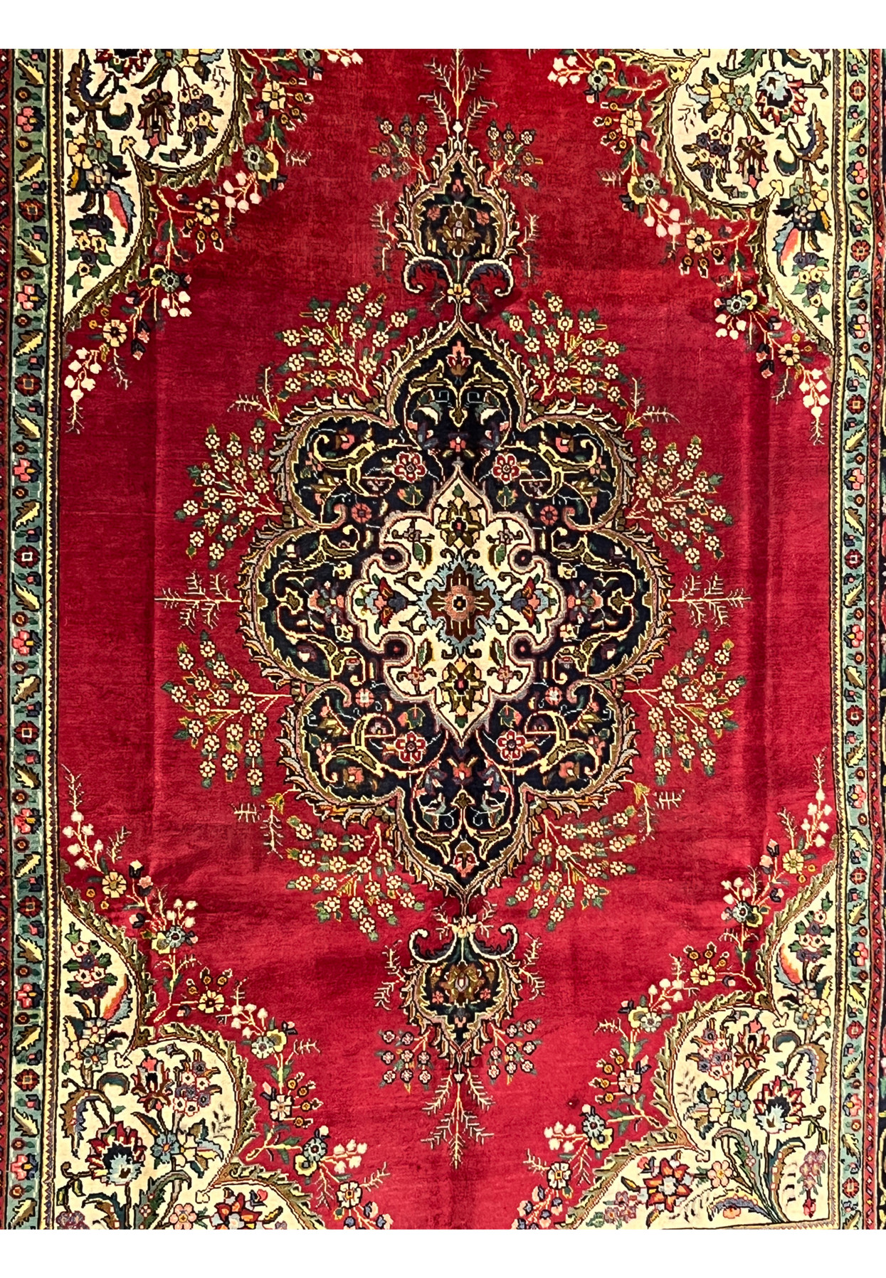 Closeup of Persian Kerman midfield showing layered cartouche medallion with navy lobes and ivory inner reserve on deep red ground