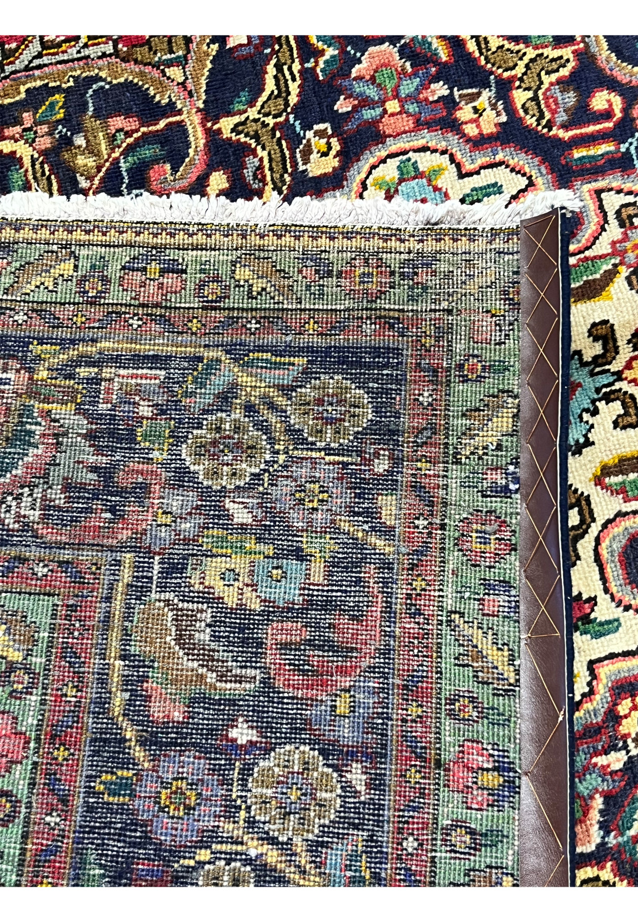 Backside corner of authentic Persian Kerman rug showing hand-knotted construction, dense weave structure, and natural ivory cotton fringe