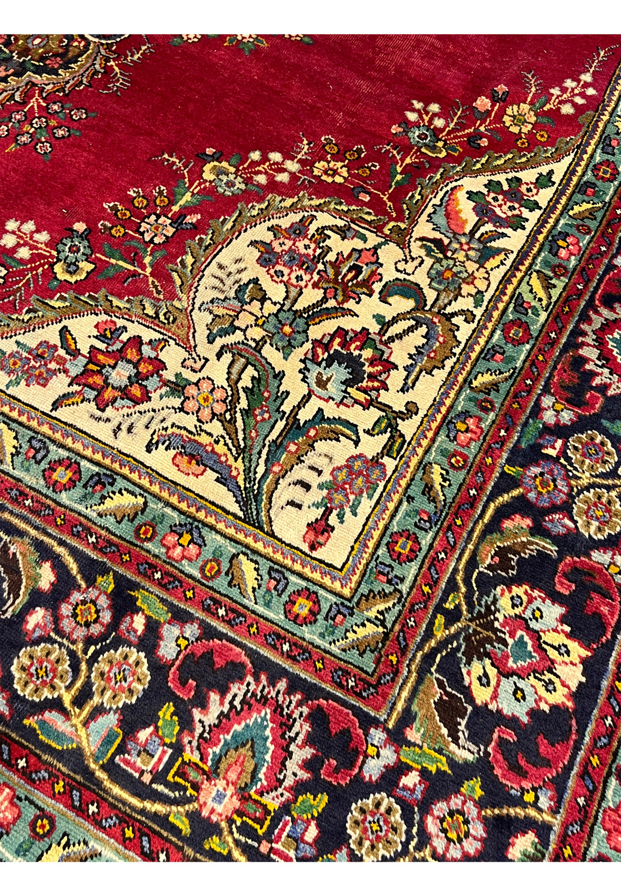 Inner border closeup of Persian Kerman rug showing turquoise green minor border with red and gold floral repeats flanking navy main border