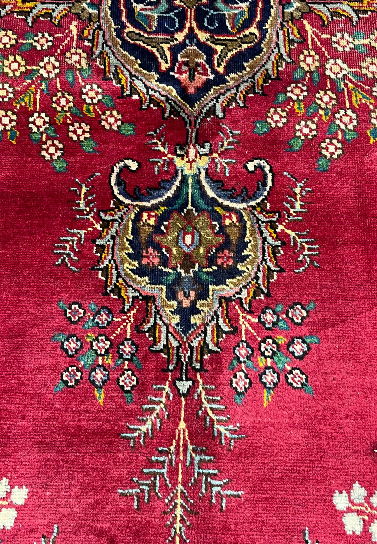 Closeup of Persian Kerman patterns and motifs showing wildflower sprays, scrolling vines, and palmette buds woven on crimson ground