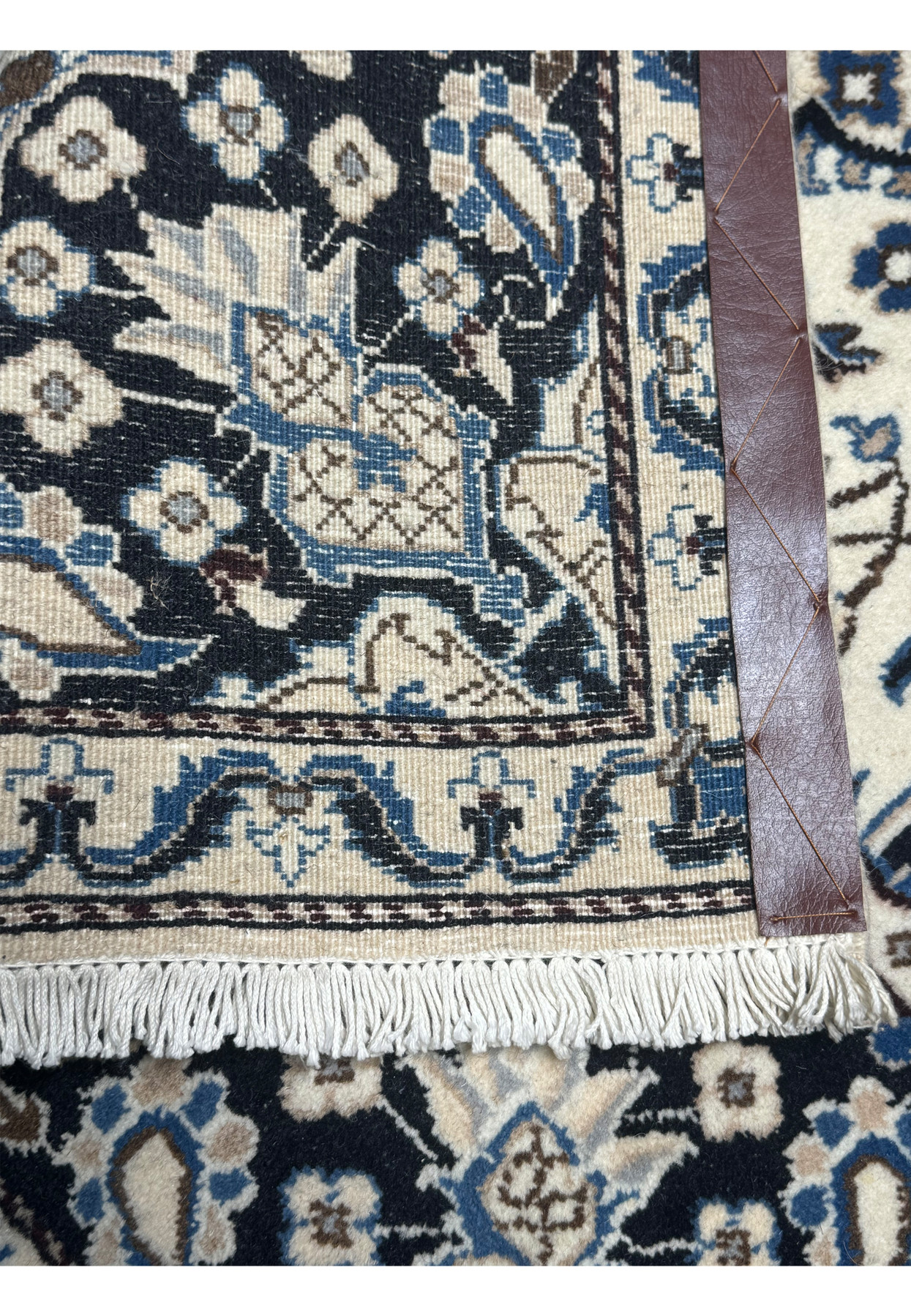 Backside corner view of Persian Nain rug showing fine knot grid, cotton foundation, and clean leather corner reinforcement