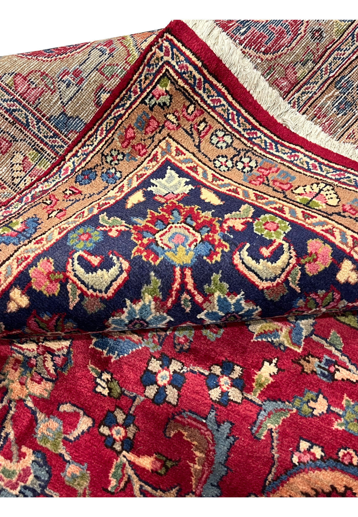 Folded-edge view of Persian Mashad showing border structure, navy main with caramel inner, hand-knotted wool authentic