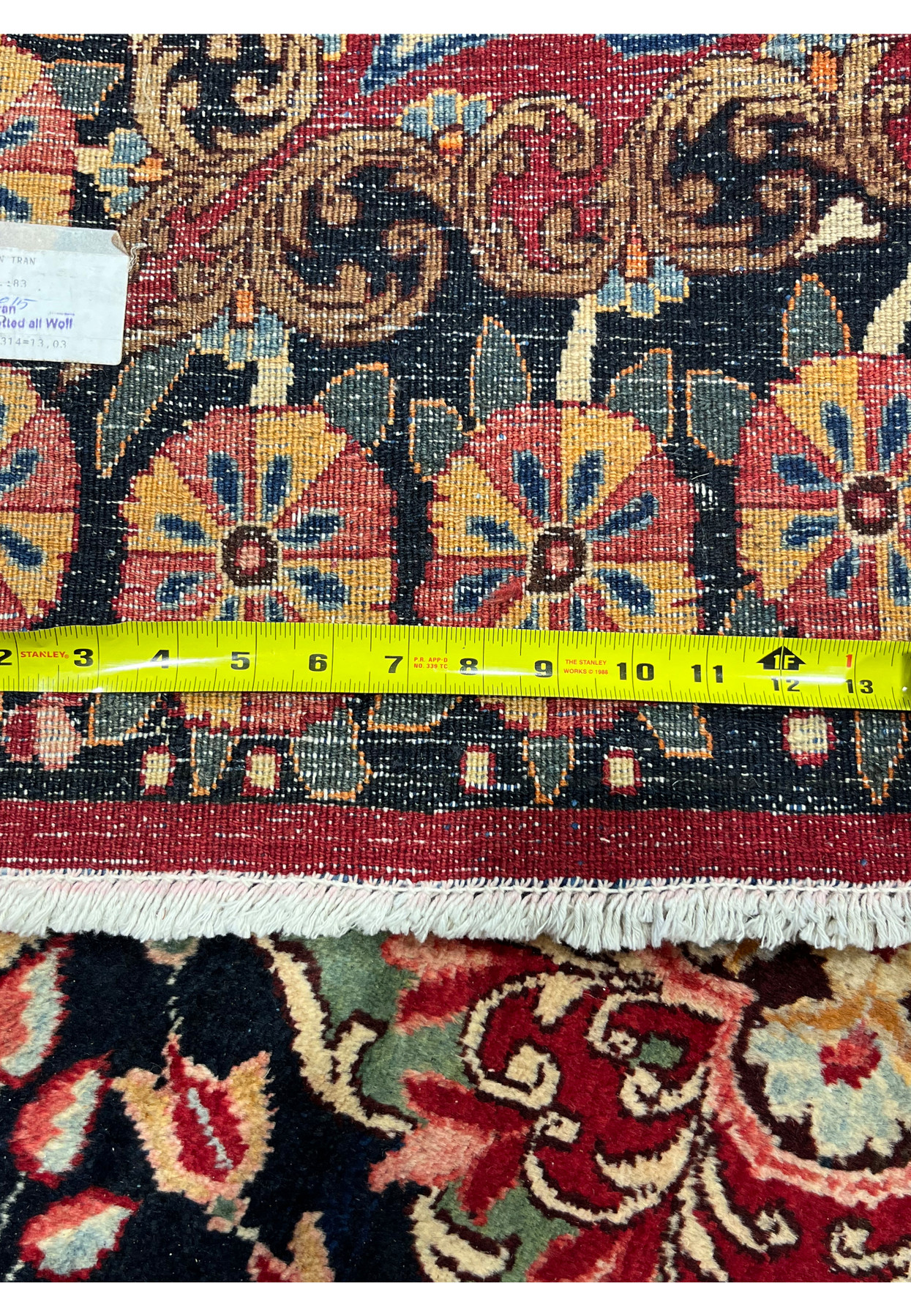 Backside knot density measured on antique signed Moud rug, ruler showing dense knot count, approximately 280 to 300 KPSI