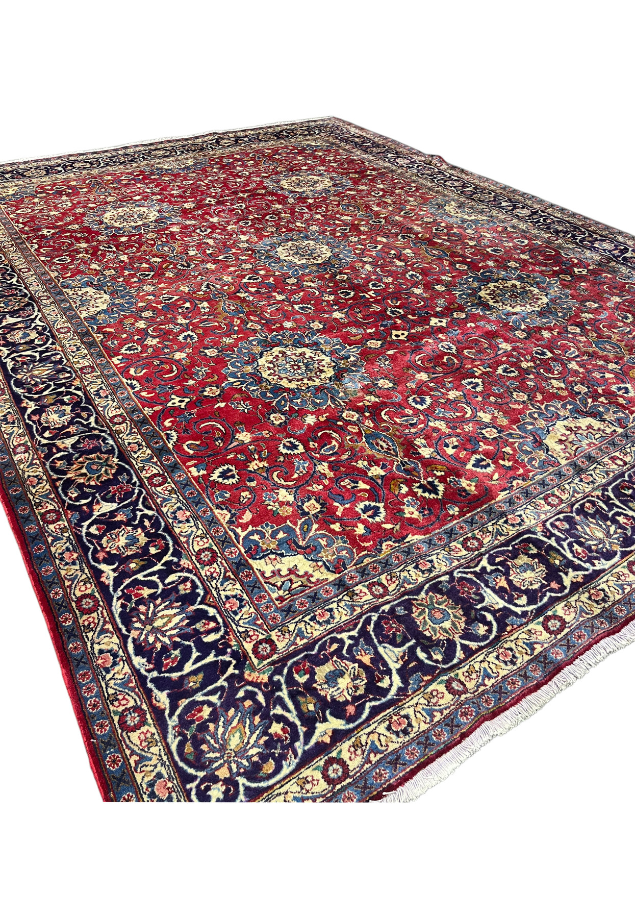 Angled view of oversize 10x13 Persian Isfahan rug, navy border and red field with allover floral, fine wool on cotton for formal living room
