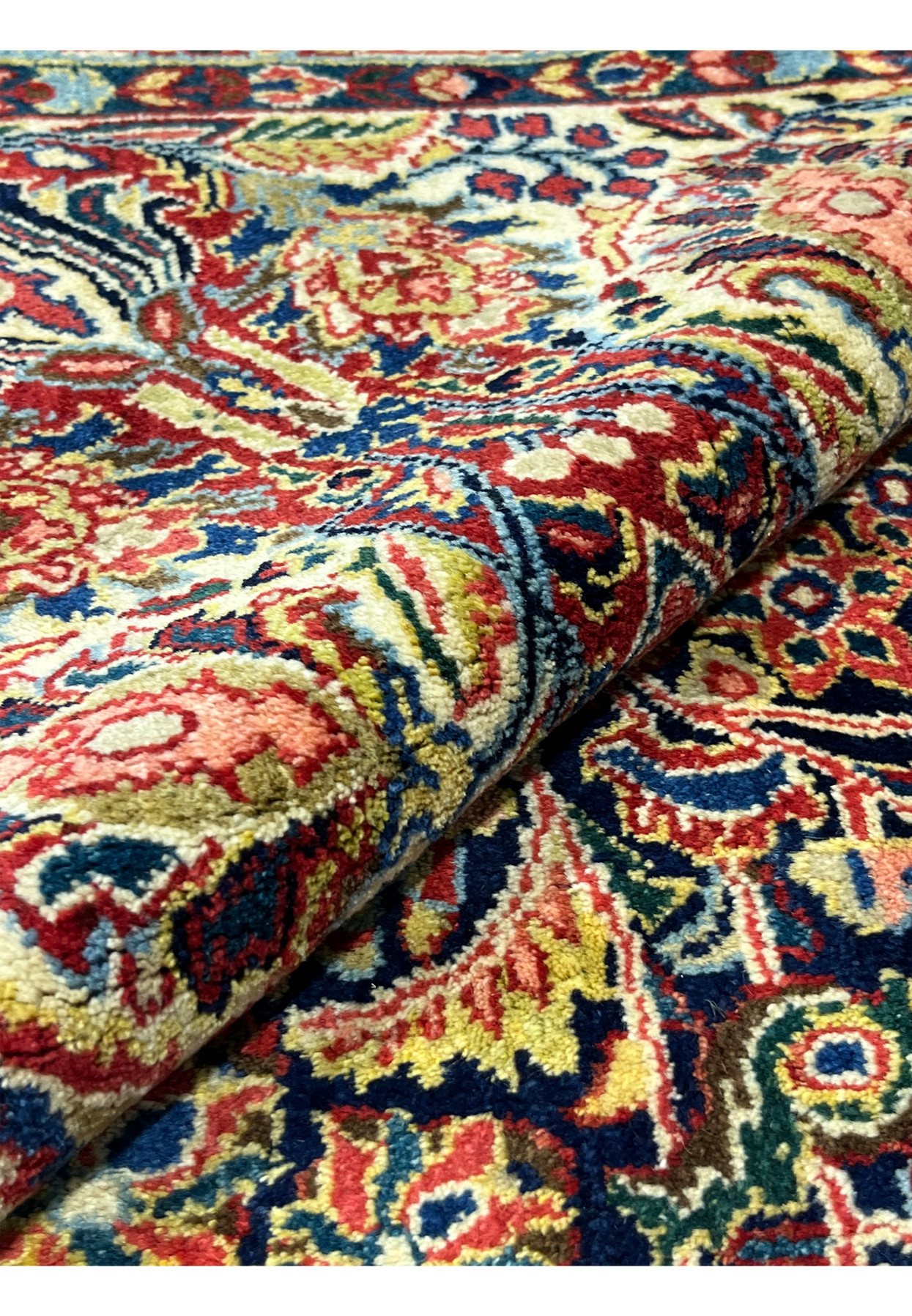 Rolled view of antique Persian Sarough rug showing full pile and saturated dye colors, never used condition