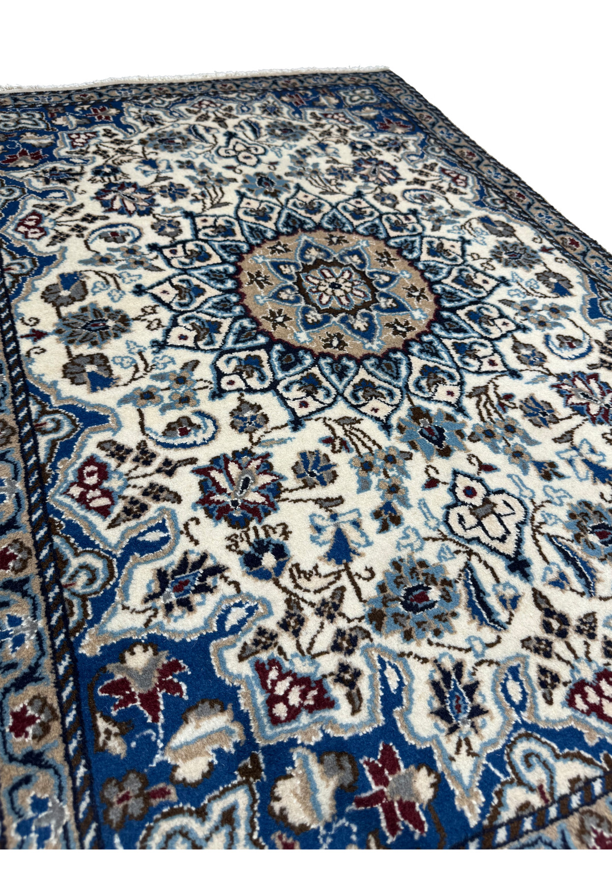 Angled view of authentic 3x4 Persian Nain rug showing full pile and saturated ivory and blue palette