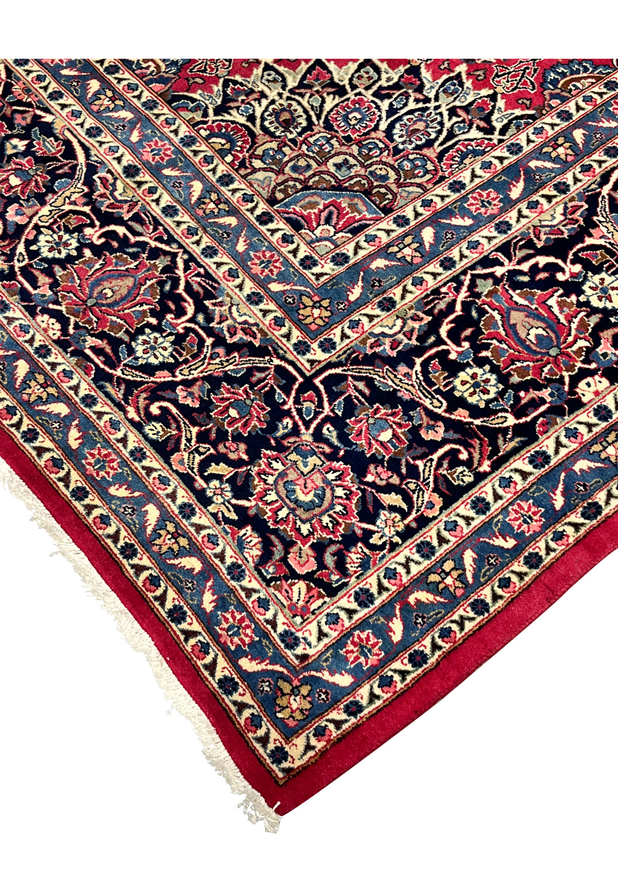 Edge view of Persian Mashad rug, cherry red field meeting navy floral border with sky blue guard stripe