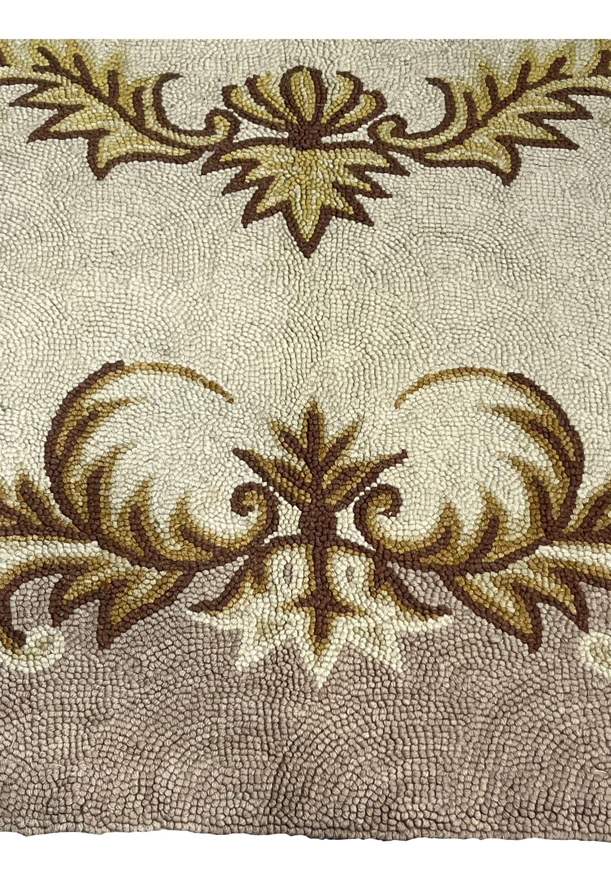 Brown and gold acanthus shell cartouche detail on the cream field of a vintage hand-hooked rug