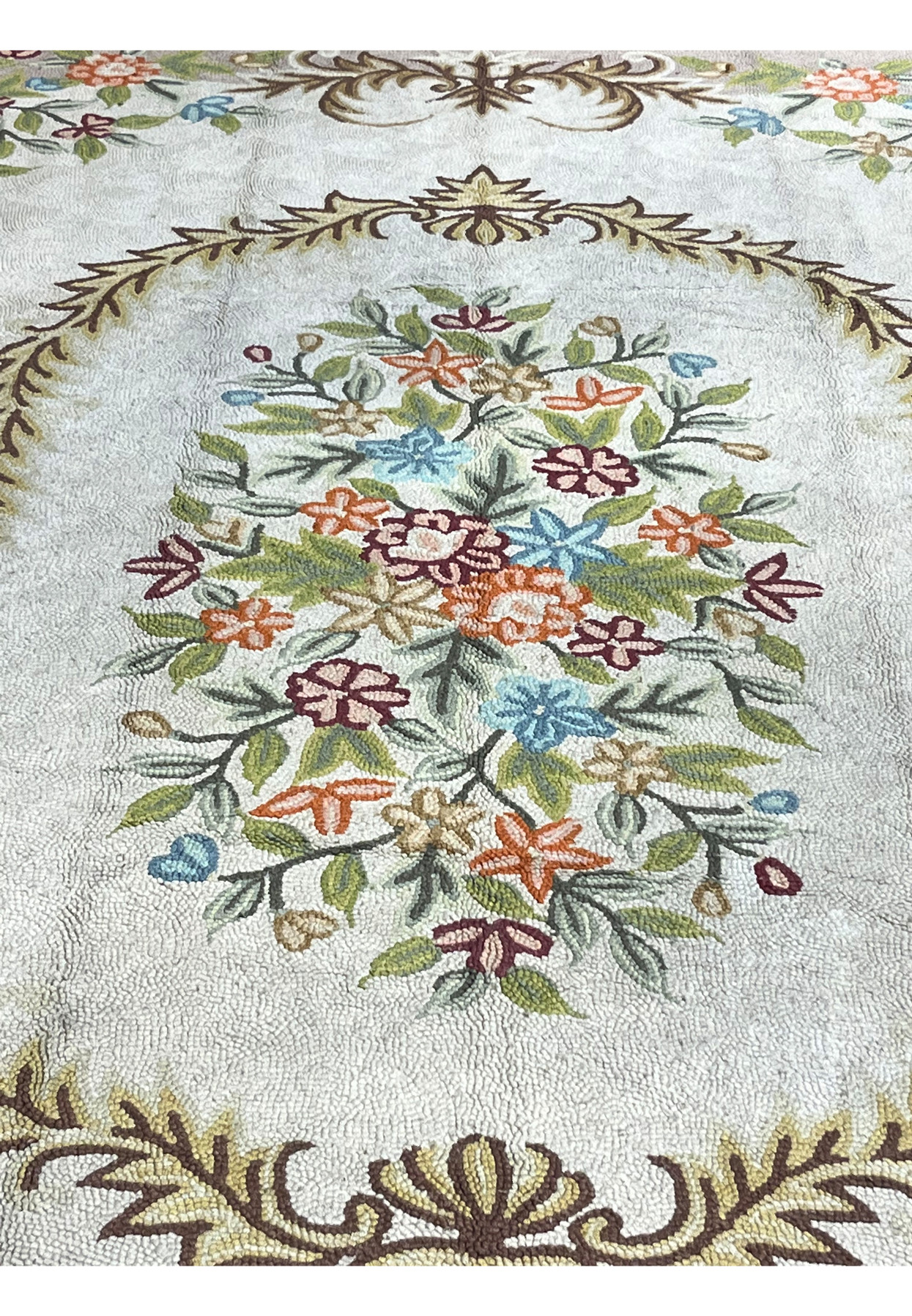 Central floral bouquet medallion of roses and wildflowers framed by a leafy laurel wreath on cream