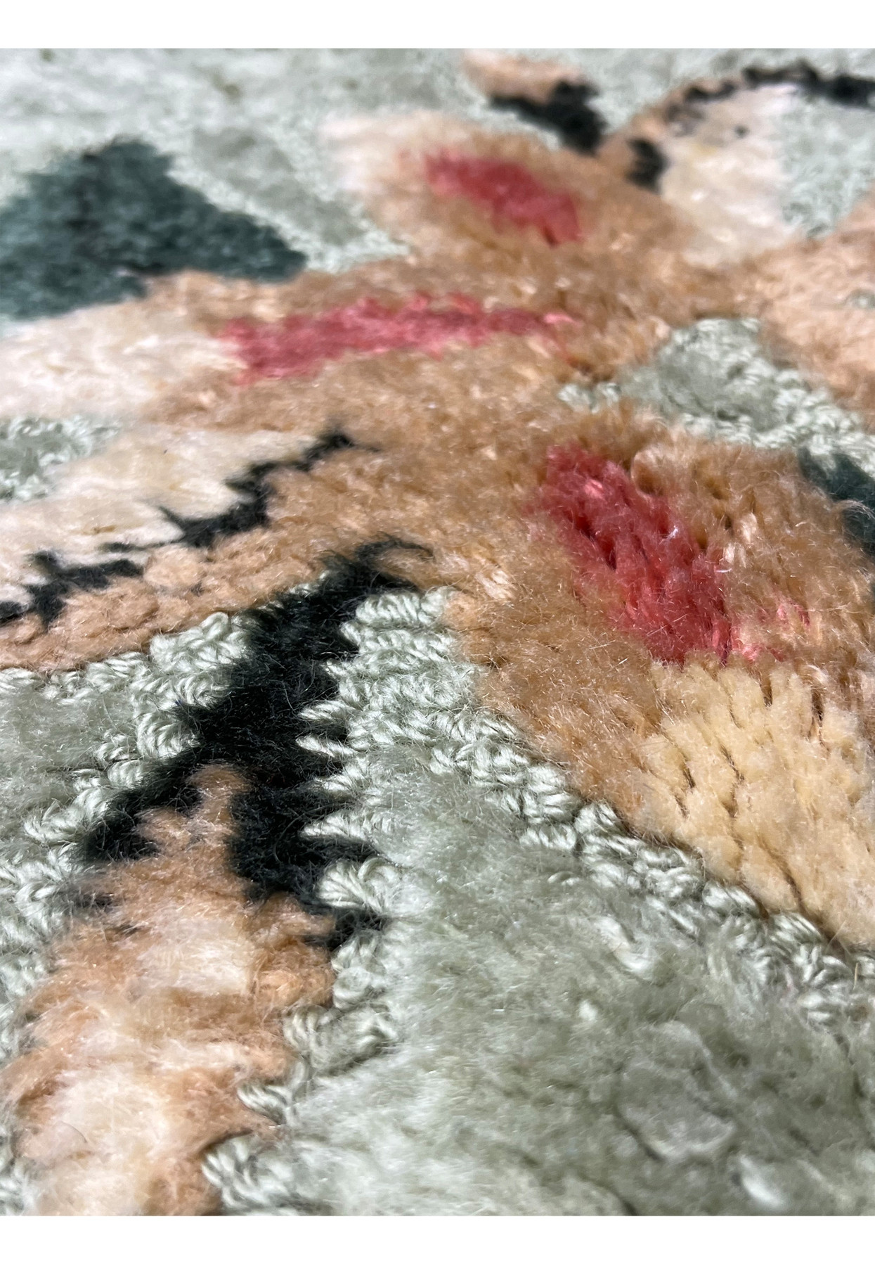 Close pattern detail of hand-hooked wool rug showing peach, rose, and cream looped pile flowers