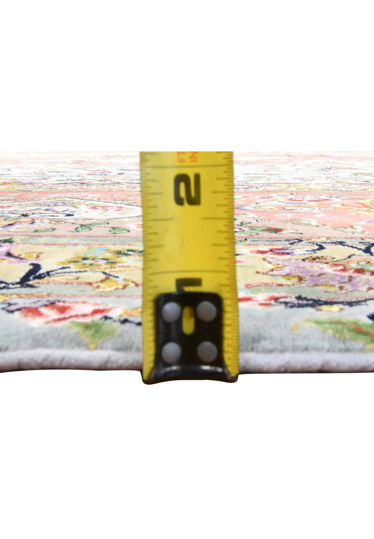 Edge thickness of a fine Persian Tabriz wool and silk rug shown against a tape measure