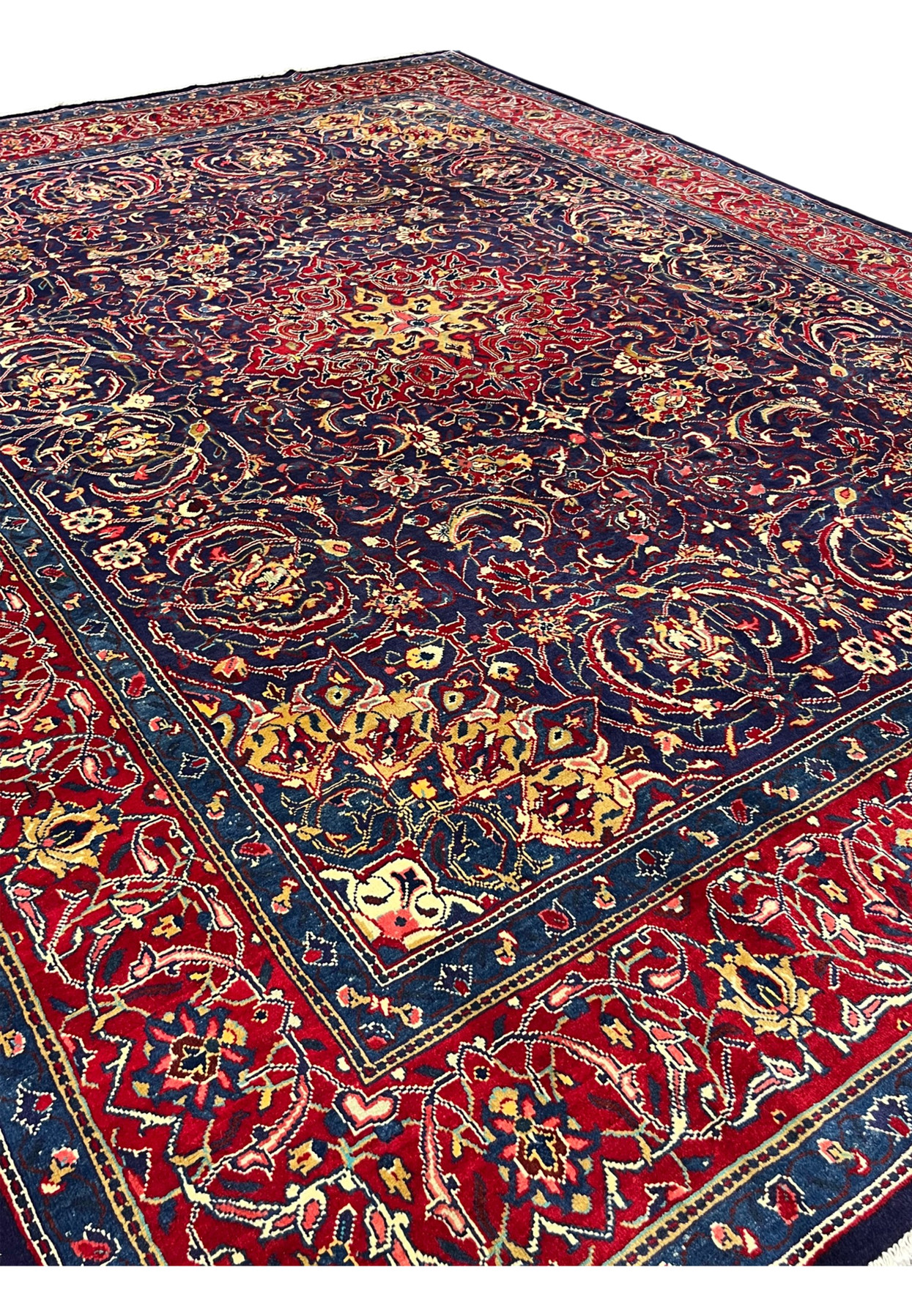 Angled view of 10x13 navy Mahal rug showing red border and allover floral field, hand-knotted wool