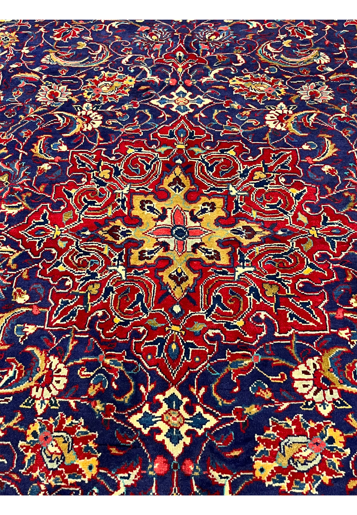 Center detail of navy Mahal rug showing gold and rose star accent surrounded by red palmettes
