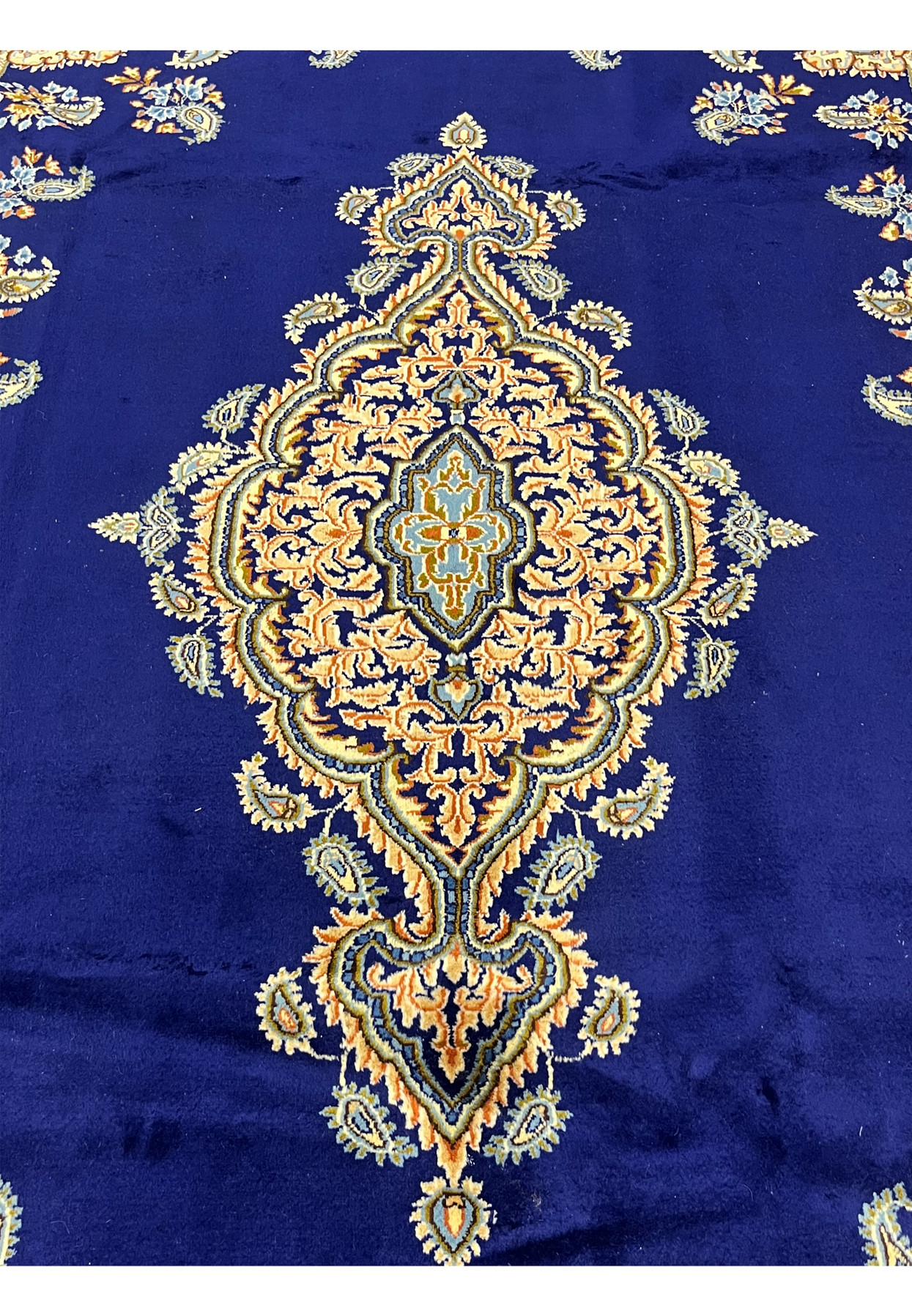 Central elongated floral medallion of Persian Yazd rug, peach and gold palmettes with sky blue diamond center on navy