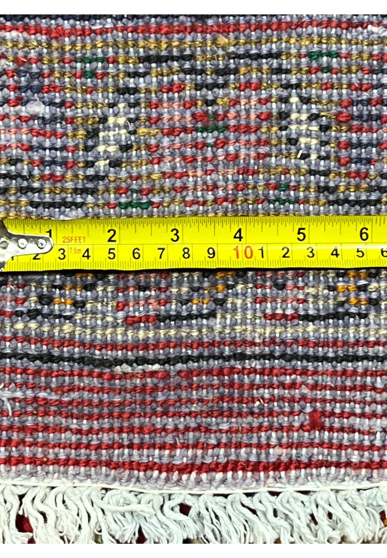 Back of the rug with a tape measure across the knots, confirming the firm hand-knotted construction