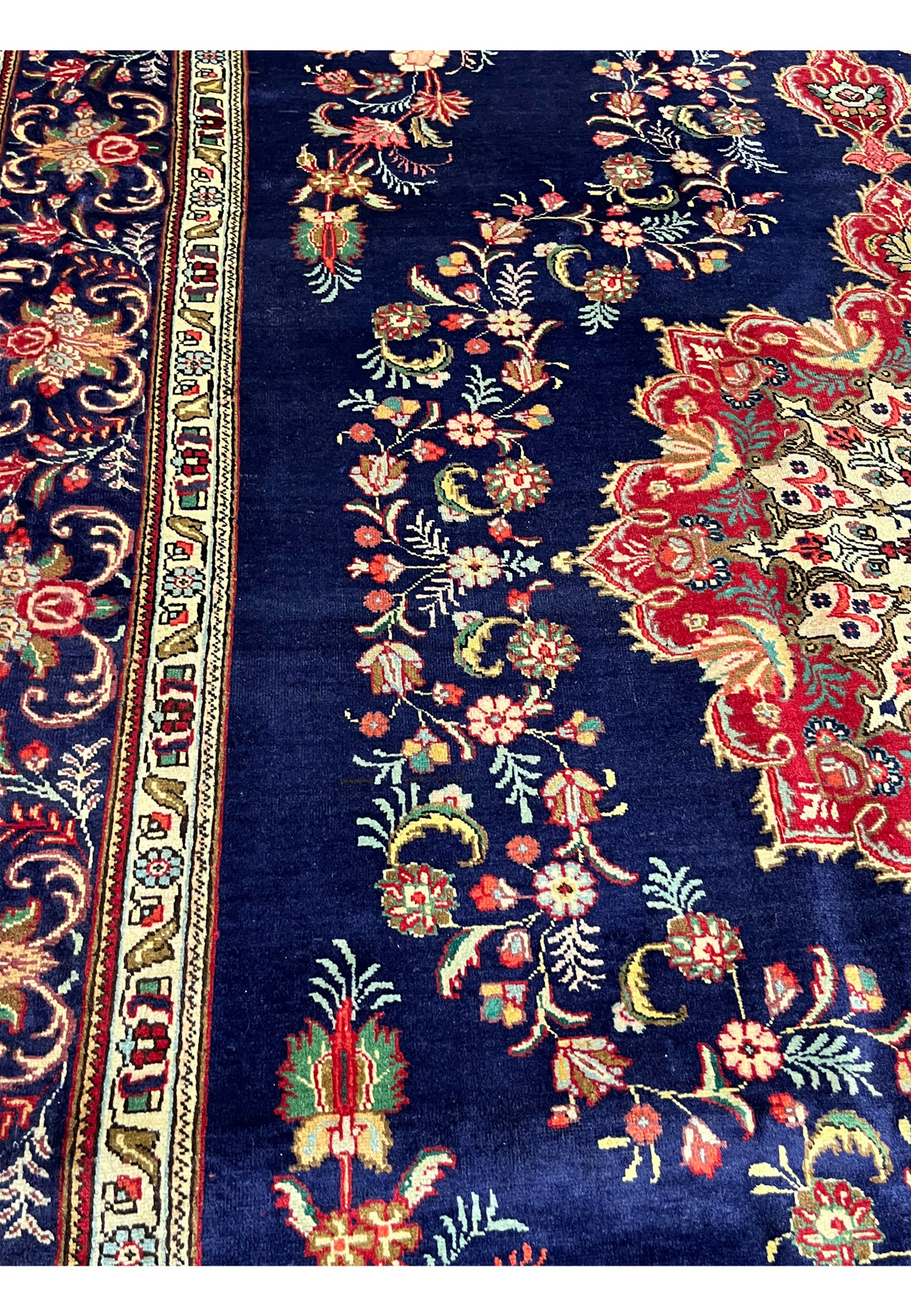 Close view of the wool pile showing red, gold, teal and ivory florals on a deep navy ground