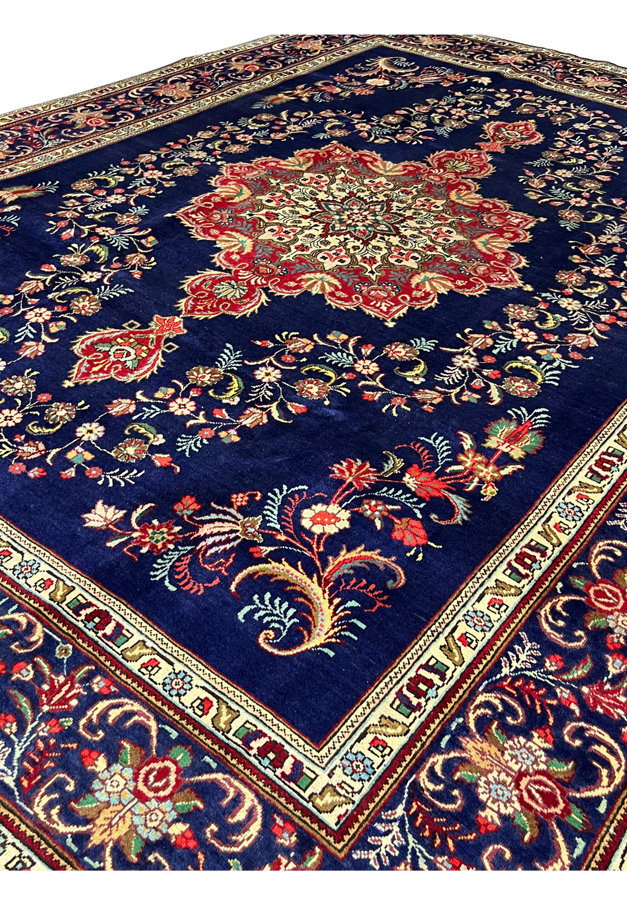 Persian Tabriz carpet seen from the side with its red medallion glowing against midnight blue wool