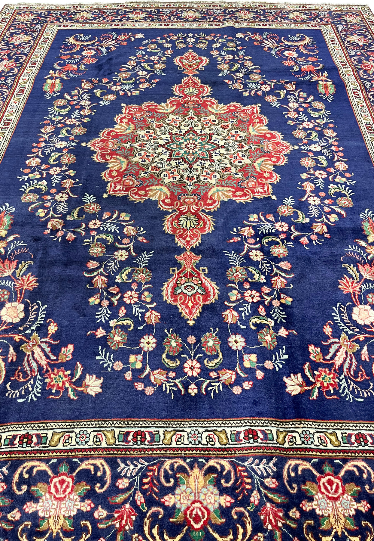 Deep navy Tabriz field scattered with floral sprays around a red and ivory central medallion