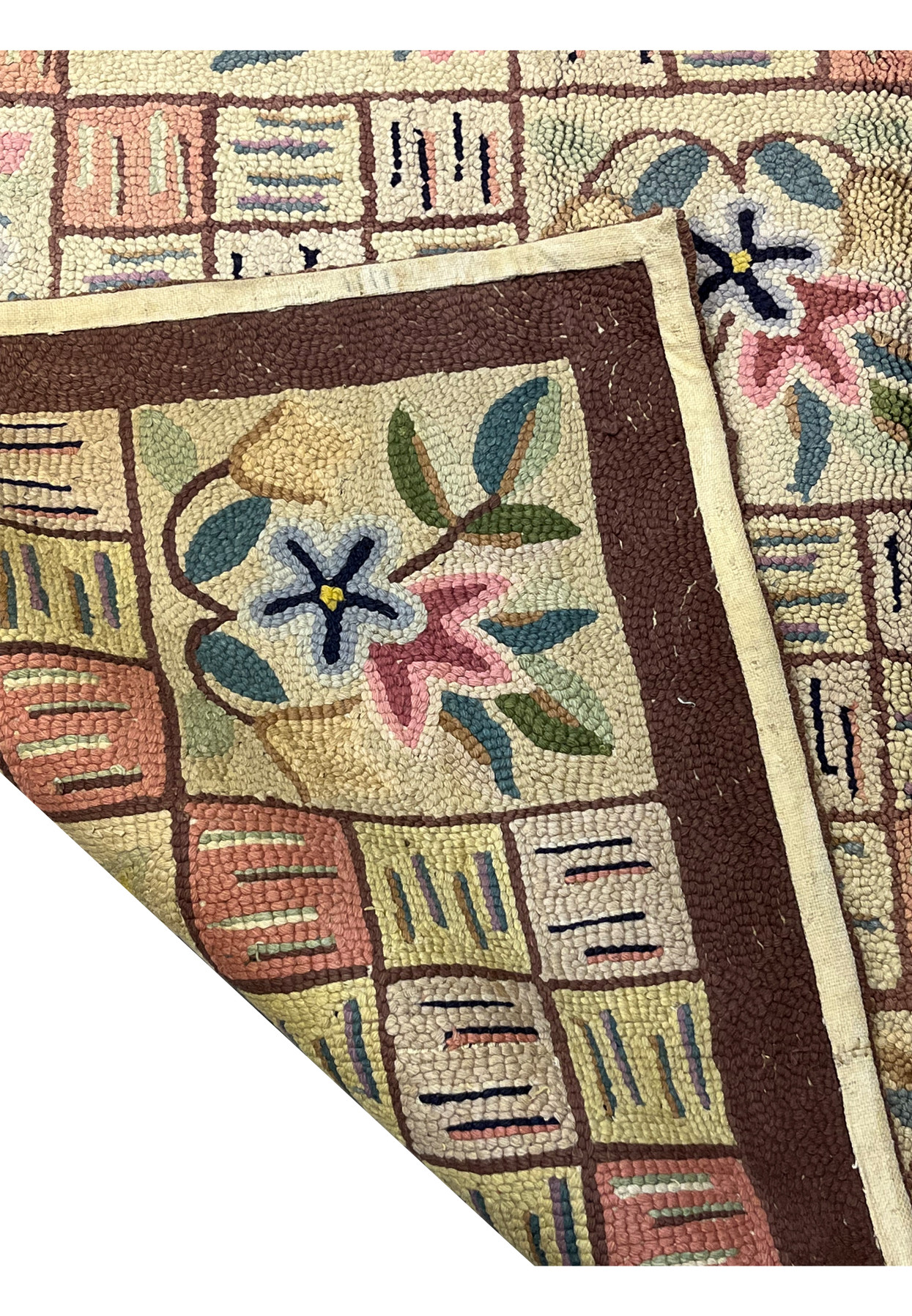 Back corner of the rug folded over showing the cotton binding and hooked construction