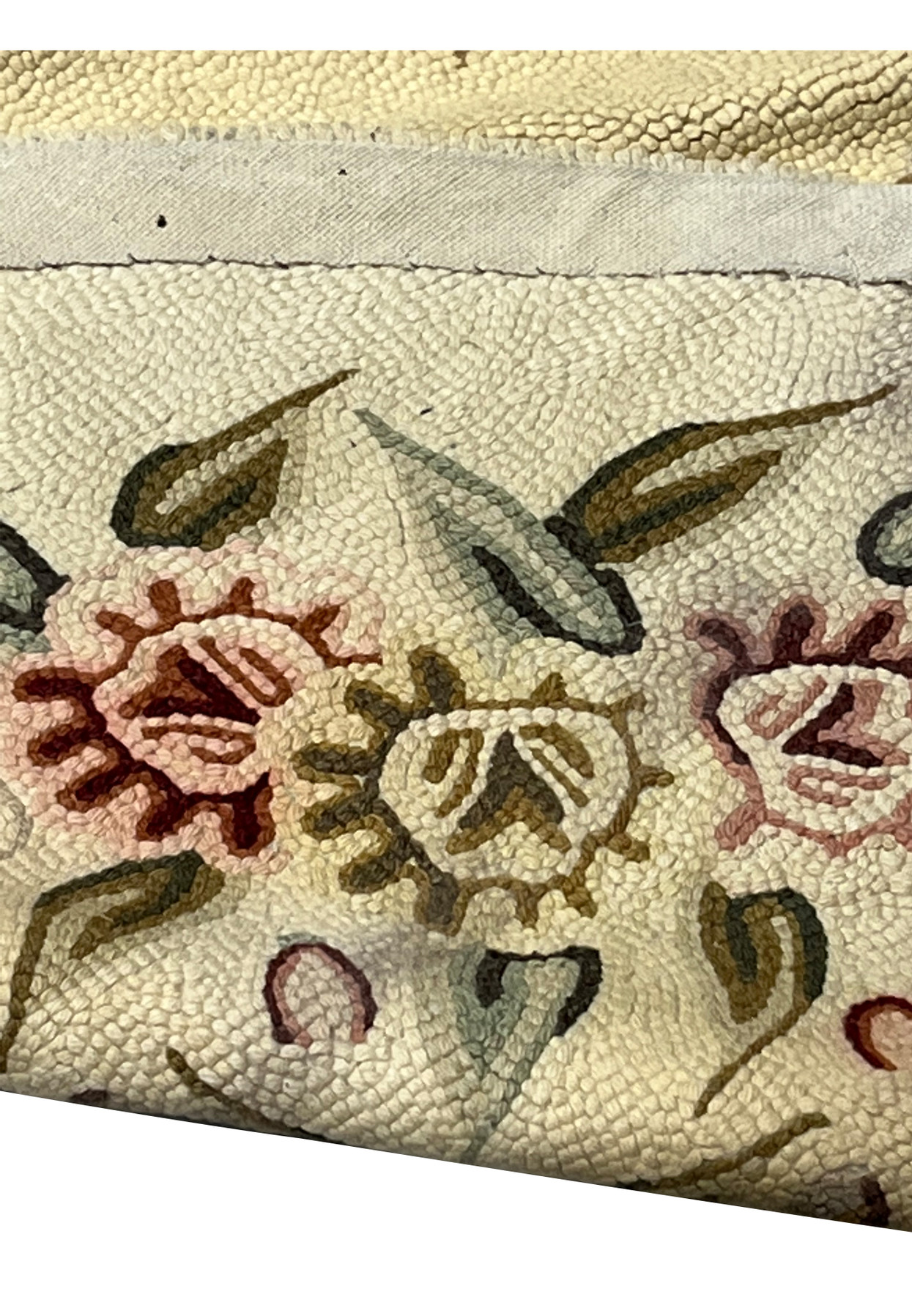 Back edge of the hand-hooked oval rug showing the looped wool pile and cotton binding