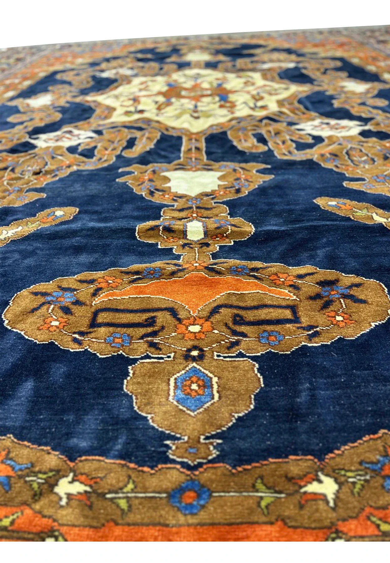 Detail of the finely knotted wool pile showing orange leaf motifs on the navy ground
