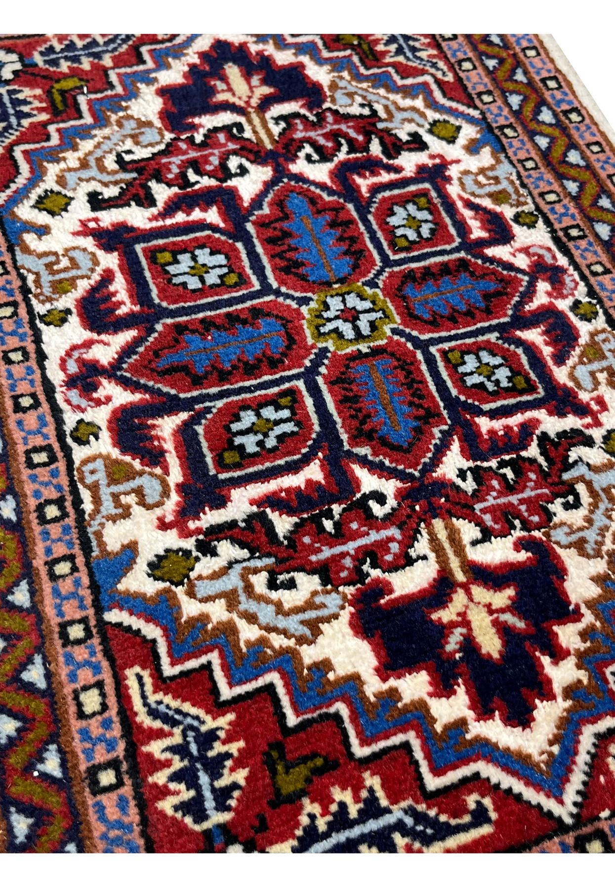 Angled view of the wool and silk Ardebil rug showing pile sheen across the red field