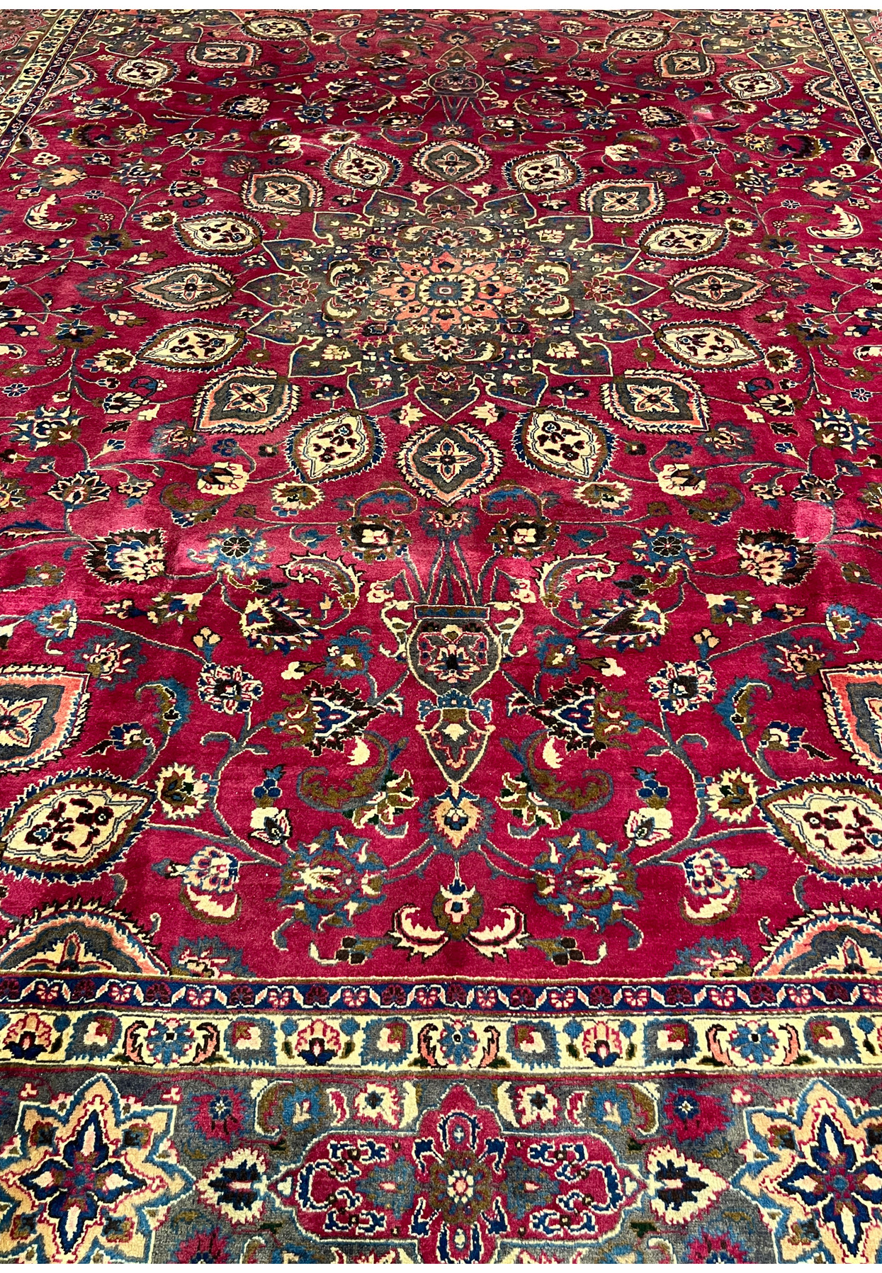 Detailed mid-field of the Mashad showing palmettes, vase motifs, and vinework on deep raspberry red